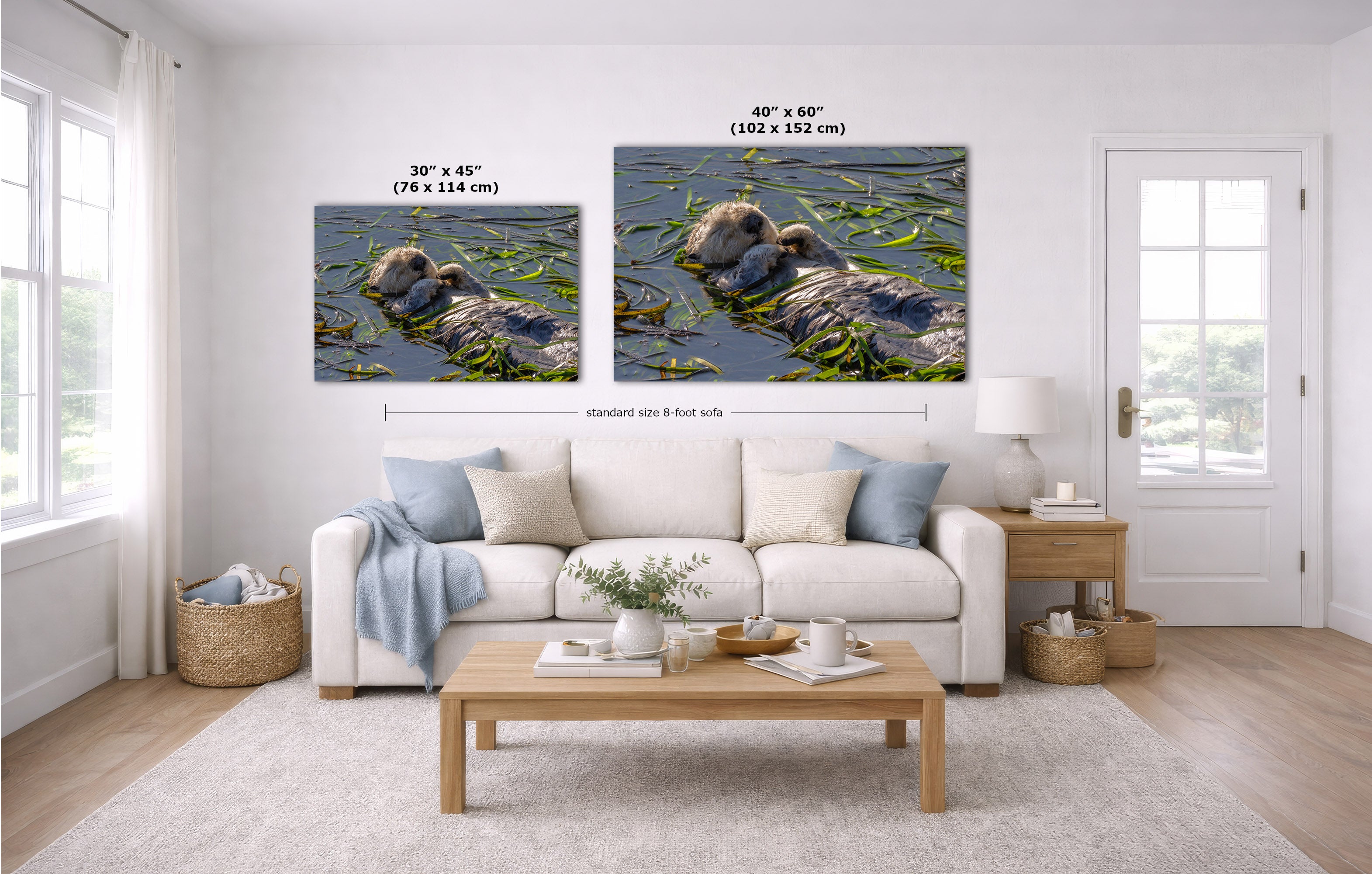 A staged living room showing two wall art prints above a white sofa. The prints depict an otter in ocean water, with size labels reading 30 x 45 inches and 40 x 60 inches.