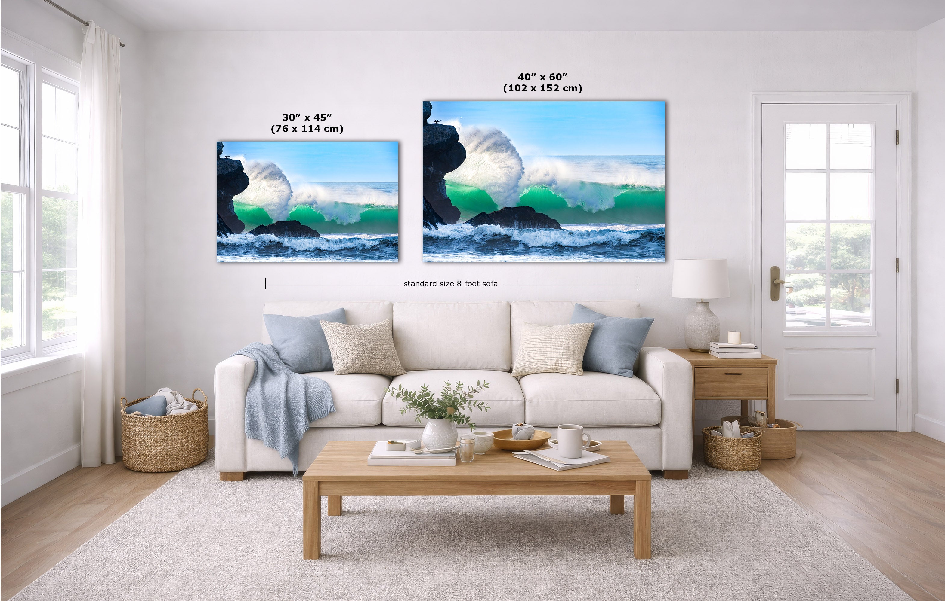 A staged living room with a white sofa, coffee table, and two ocean-wave wall art prints above the couch. The prints show black rock cliffs, white surf, and blue-green water, with size labels and dimension lines overlaid on the image.