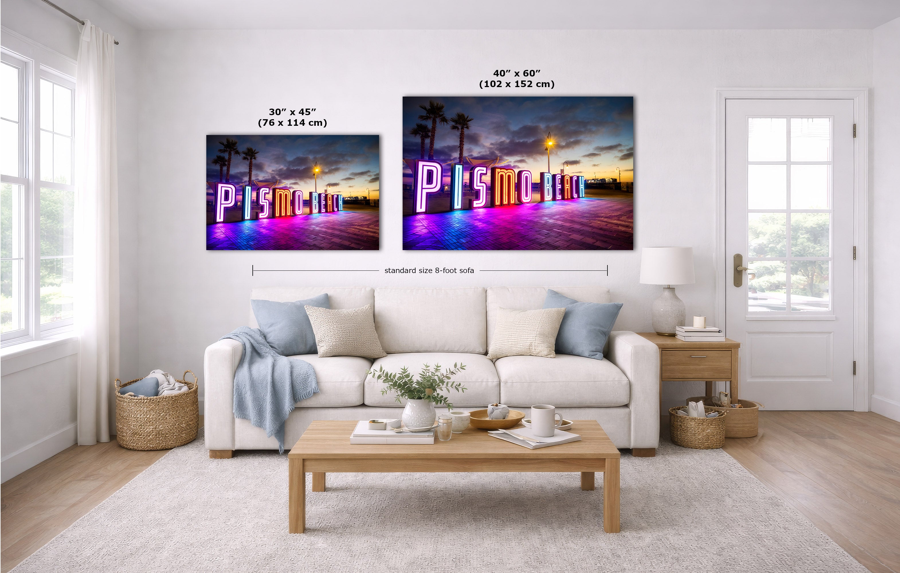A staged living room shows two wall art prints above a white sofa. The prints depict a colorful neon-style 'Pismo Beach' sign at sunset with palm trees.