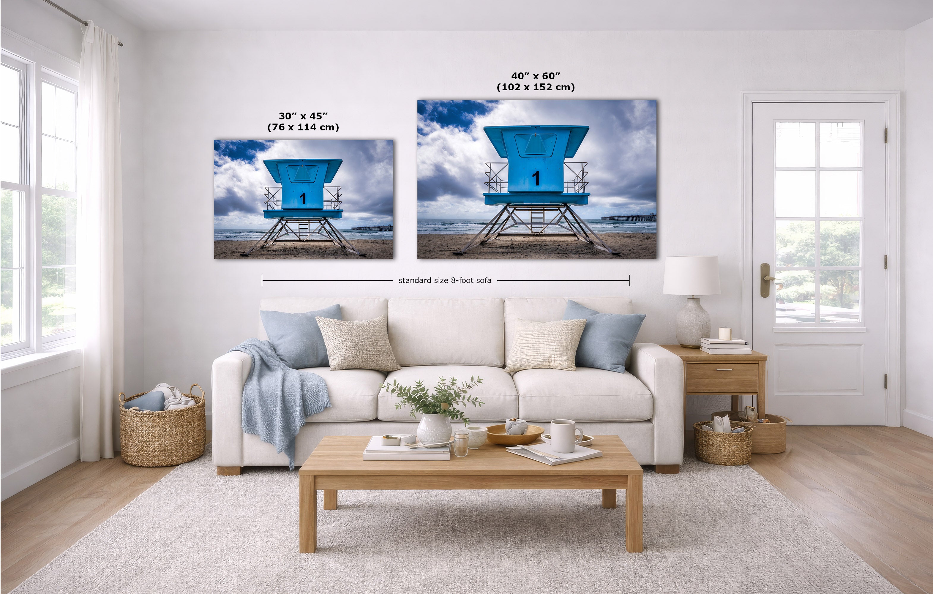 A staged living room shows two vertical wall art prints above a white sofa. Each print depicts a bright blue lifeguard tower scene with clouds and water, and size text is overlaid above each frame.