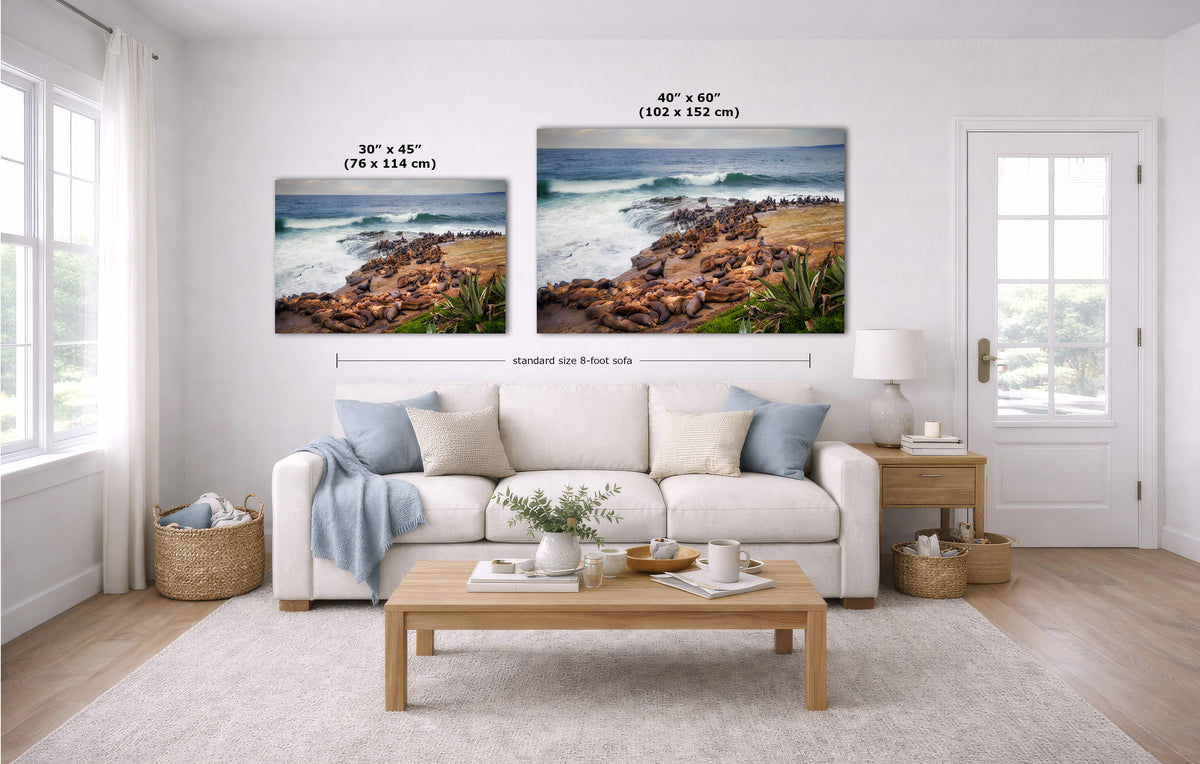 Two coastal landscape wall art prints shown in a bright living room above a white sofa, with size labels indicating 30 x 45 inches and 40 x 60 inches.
