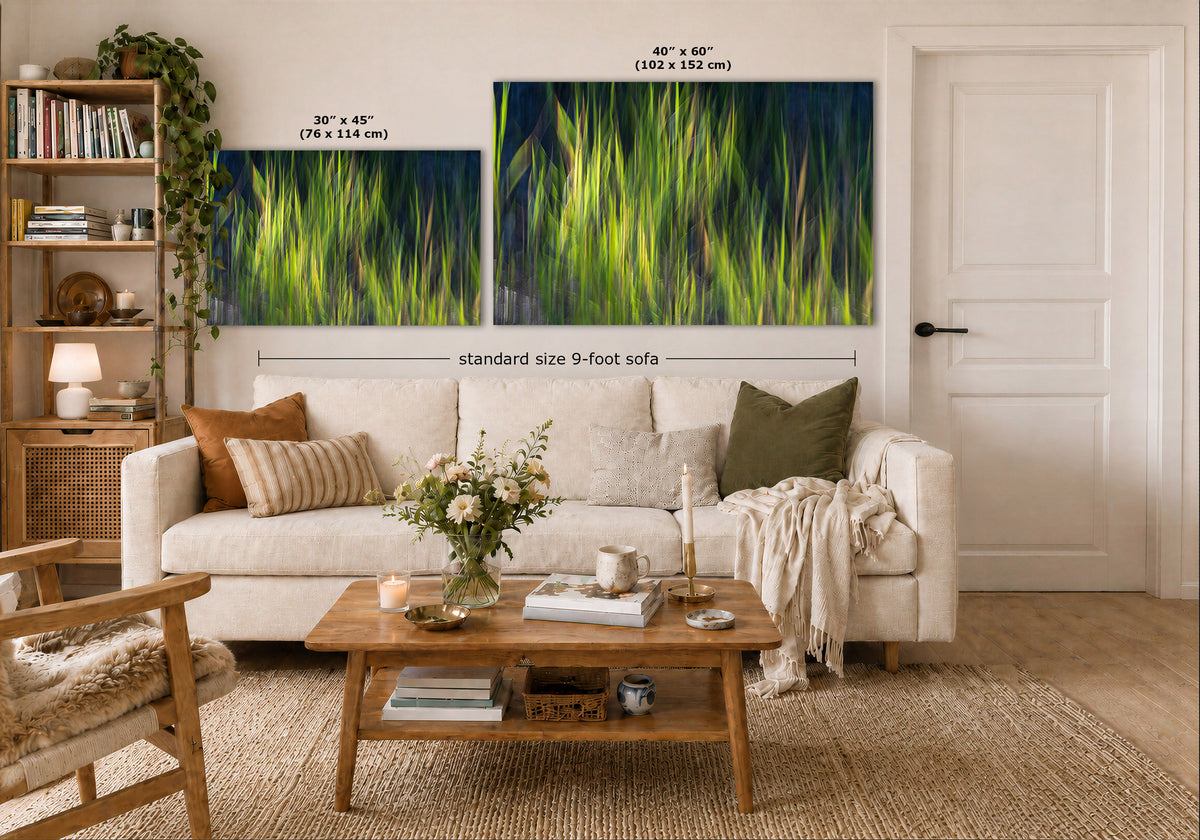 A styled living room showing two large wall art prints above a white sofa. The prints depict bright green grass or reeds against a dark navy blue background.