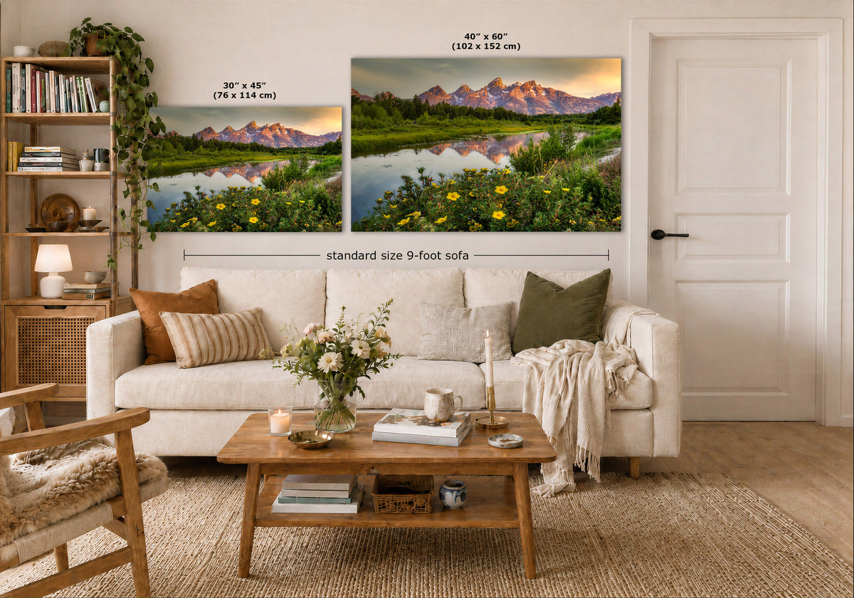 Two wall art prints showing mountain lake landscapes are displayed above a white sofa in a styled living room. The left print is labeled 30 x 45 in, and the right print is labeled 40 x 60 in, with a note for a standard size 9-foot sofa.