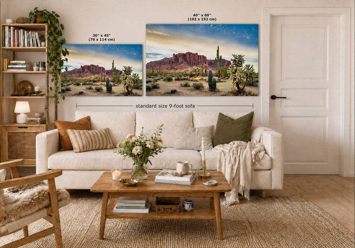 A staged living room shows two desert landscape wall art prints above a white sofa. The left print is labeled 30 x 45 inches, and the larger right print is labeled 40 x 60 inches, with a note about a standard size 9-foot sofa below.