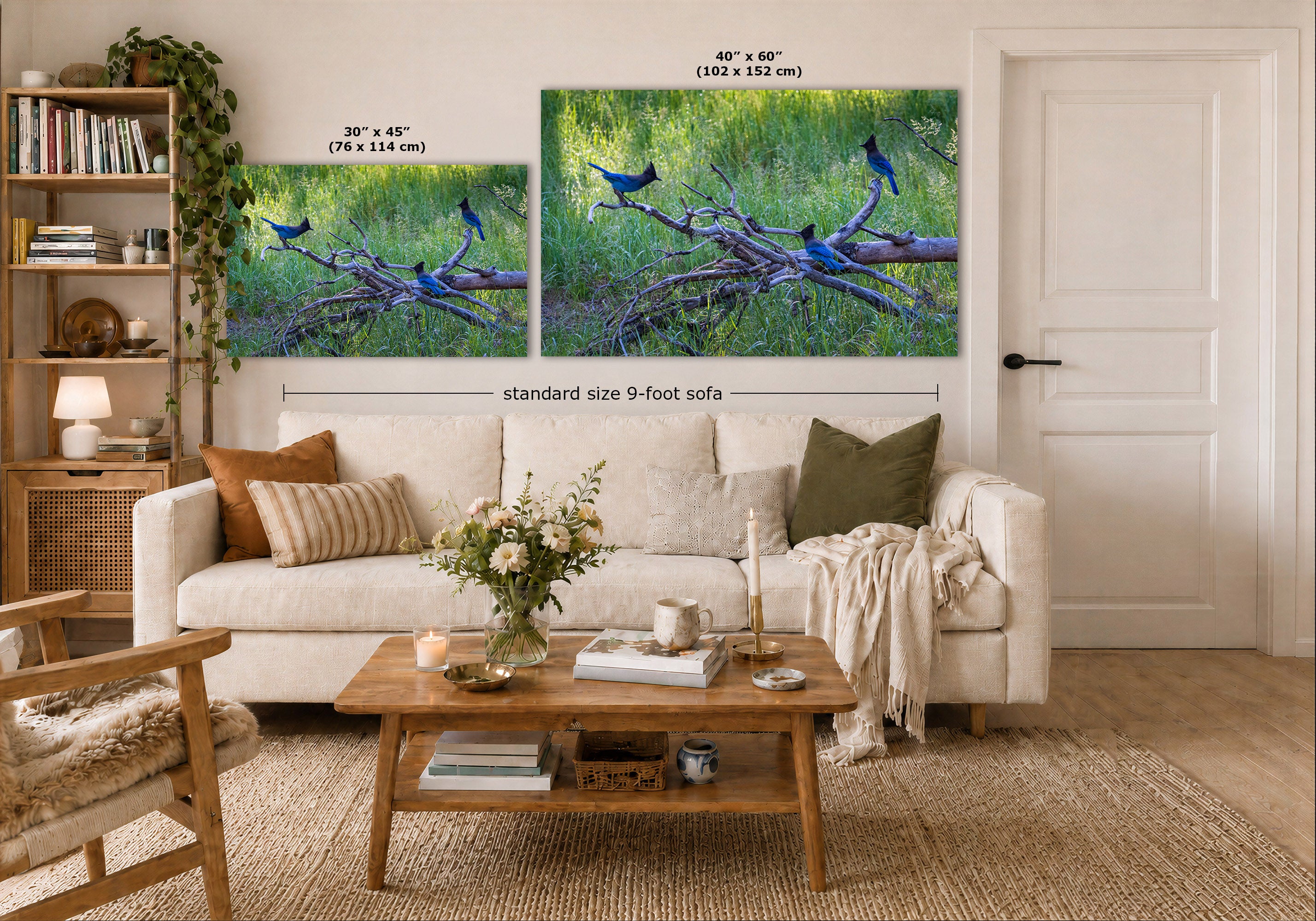 Two wall art prints showing Stellar's jay blue birds perched on branches in a grassy green landscape, displayed above a white sofa in a styled living room. One print is labeled 30 x 45 inches and the other 40 x 60 inches, with a dimension note for a standard 9-foot sofa.