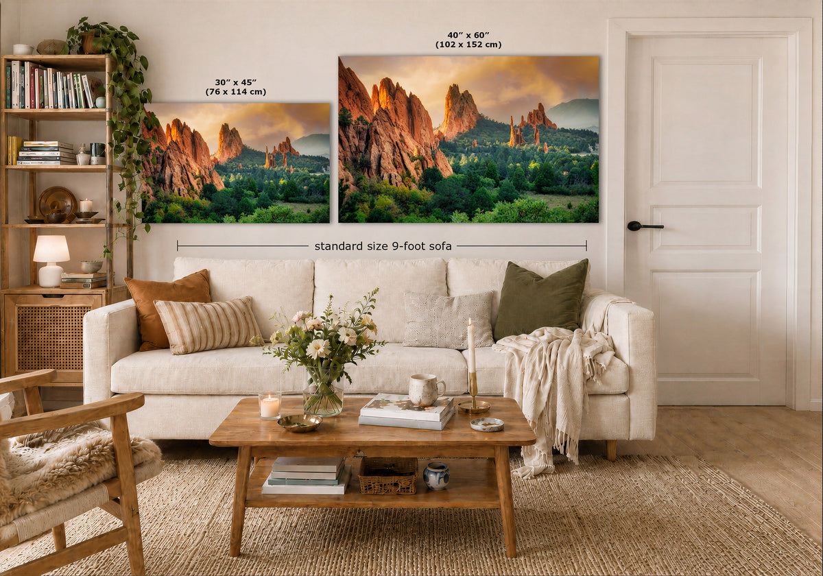 A staged living room shows two mountain landscape wall art prints above a white sofa. The left print is labeled 30 x 45 cm and the right print 40 x 60 cm, with a note about the standard size 9-foot sofa below.