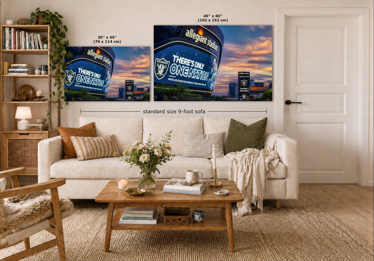 A styled living room showing two wall art prints above a white sofa. The prints depict a blue stadium crowd scene with the text 'Allegiant Stadium'.