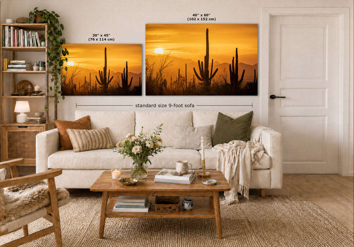 A styled living room showing two desert sunset wall art prints above a white sofa. The left print is labeled 30 x 45 inches, and the larger right print is labeled 40 x 60 inches, with a note for a standard size 9-foot sofa.