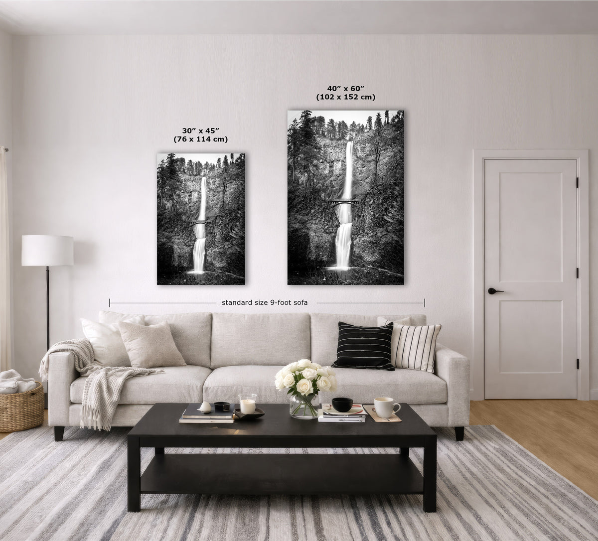 A staged living room with a light beige sofa, black coffee table, striped rug, and two vertical black-and-white waterfall wall art prints mounted above the couch. White size labels and text indicate the two print sizes: 30 x 45 inches and 40 x 60 inches (75 x 114 cm and 102 x 152 cm).