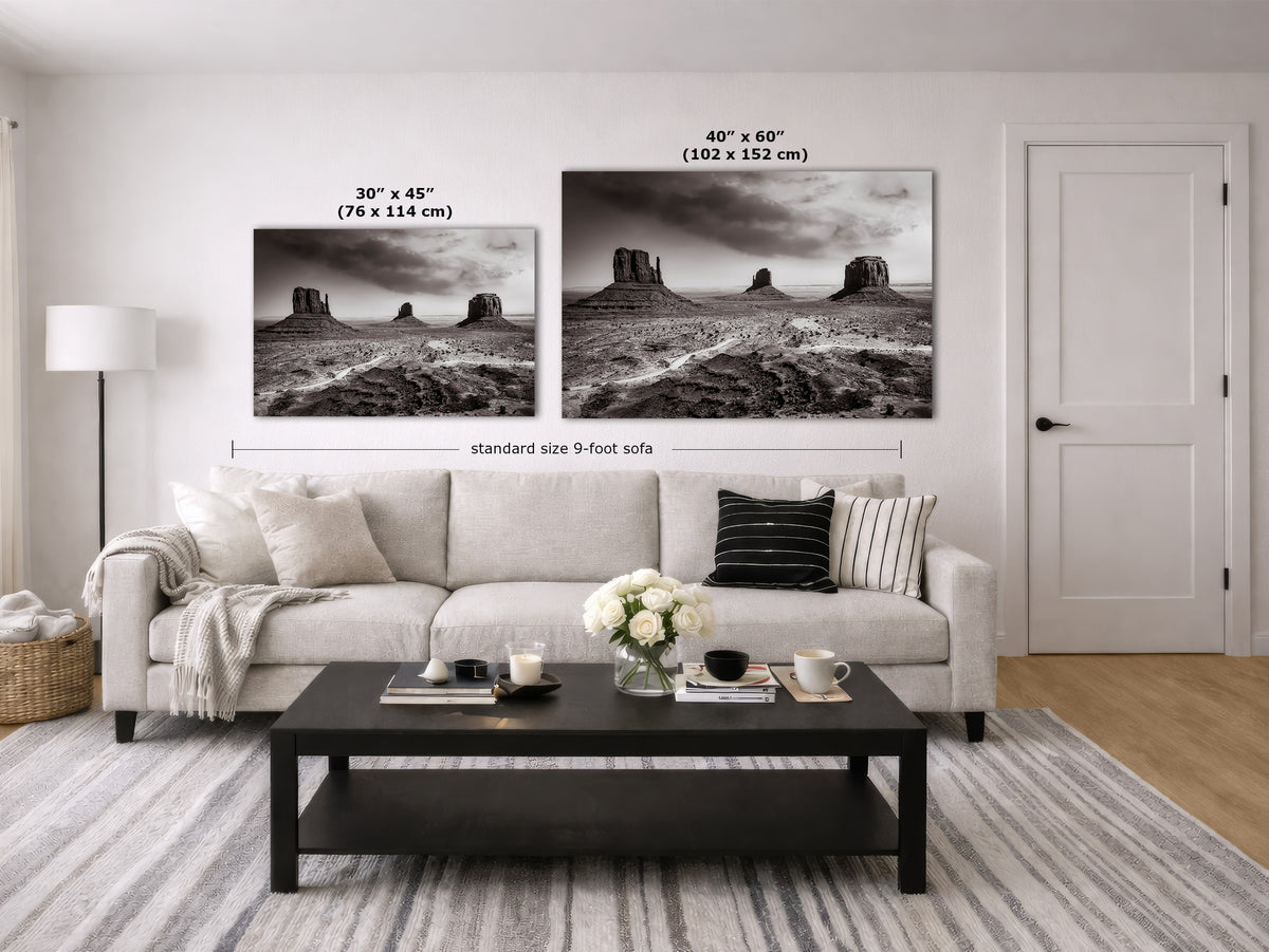 A styled living room showing two black-and-white landscape wall art prints above a light sofa, with size labels overlaid: 30 x 45 inches (76 x 114 cm) and 40 x 60 inches (102 x 152 cm).