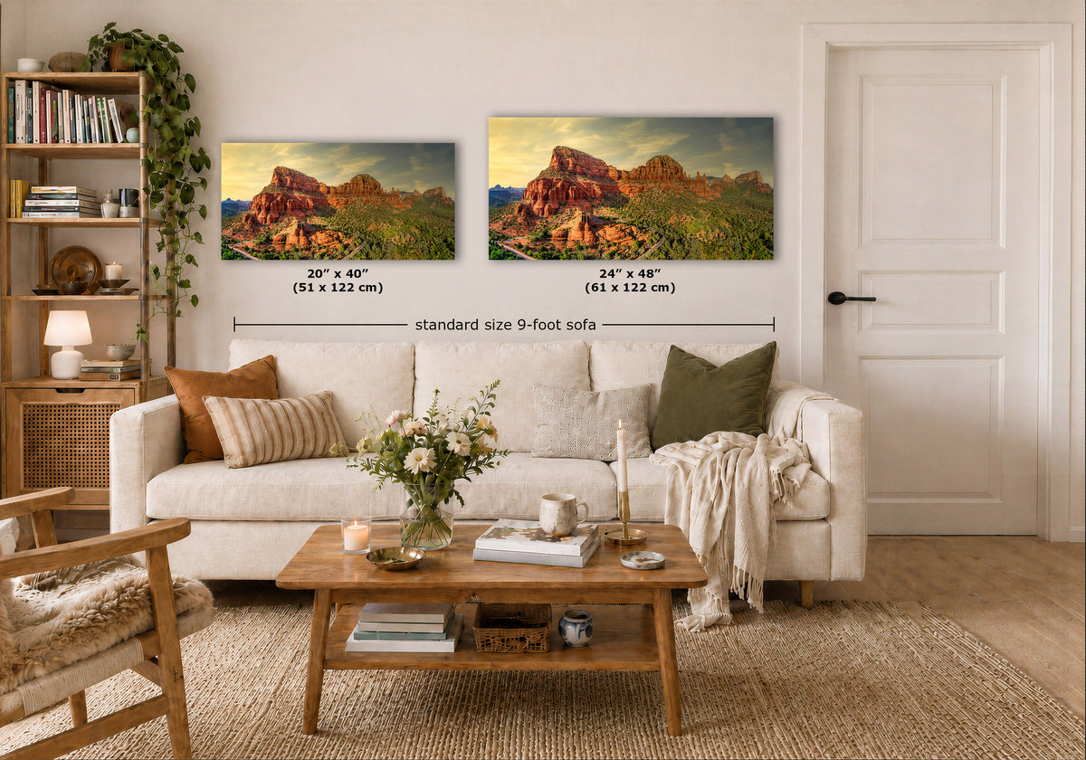 Two landscape art prints of red rock desert mountains are displayed on a white wall above a beige sofa in a styled living room. Black dimension lines and text indicate the sizes: 20" x 40" (51 x 122 cm) and 24" x 48" (61 x 122 cm), with 'standard size 9-foot sofa' written below.