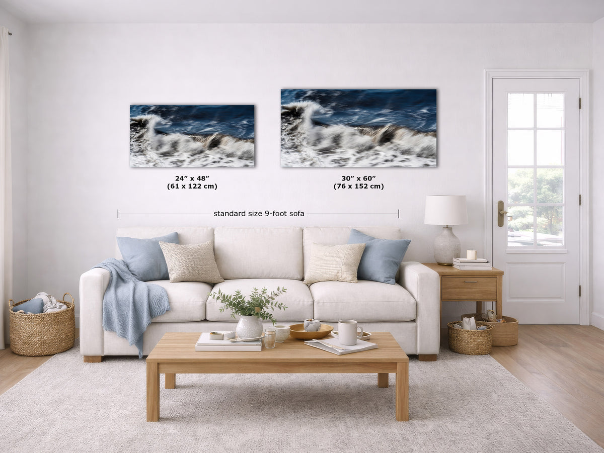 A staged living room shows a white sofa with blue and cream pillows, a wooden coffee table, and two framed ocean-wave wall art prints above the couch. Black measurement lines and text indicate the prints are 24 x 48 inches and 30 x 60 inches, with a standard size 9-foot sofa reference.