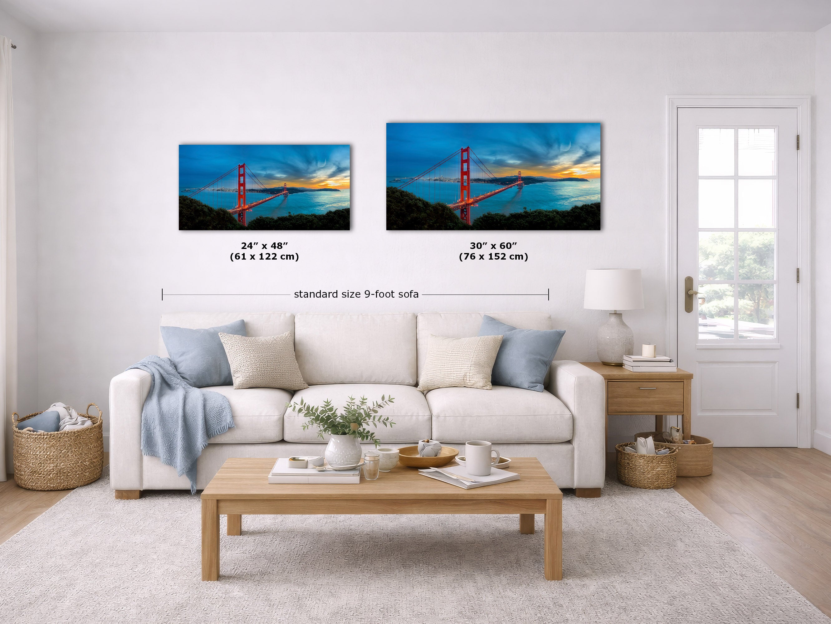 A staged living room with two framed wall art prints above a white sofa. Each print shows a colorful sunset over a red bridge over water.