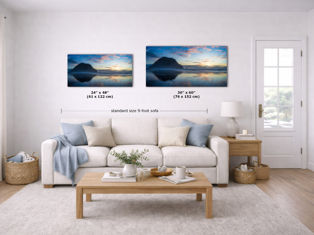 Two wall art prints showing mountain lake sunsets are displayed above a white sofa in a bright living room. Black text labels indicate the dimensions of each print: 24 x 48 inches and 30 x 60 inches, with a note reading standard size 9-foot sofa.