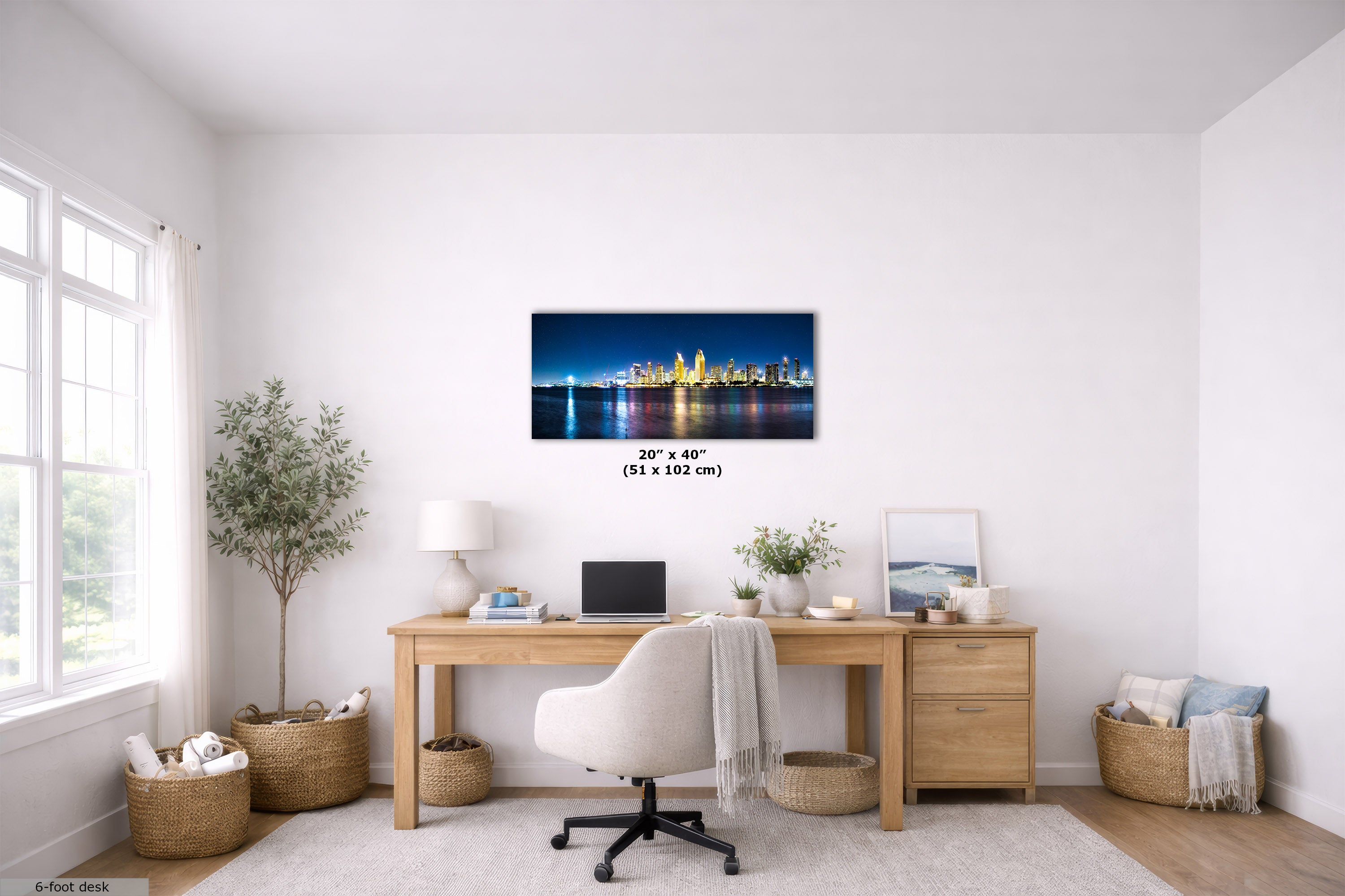 A framed horizontal canvas print of a vibrant city skyline at night hangs on a white wall in a modern, bright home office. The print features a blue and yellow illuminated skyline with reflections on water.