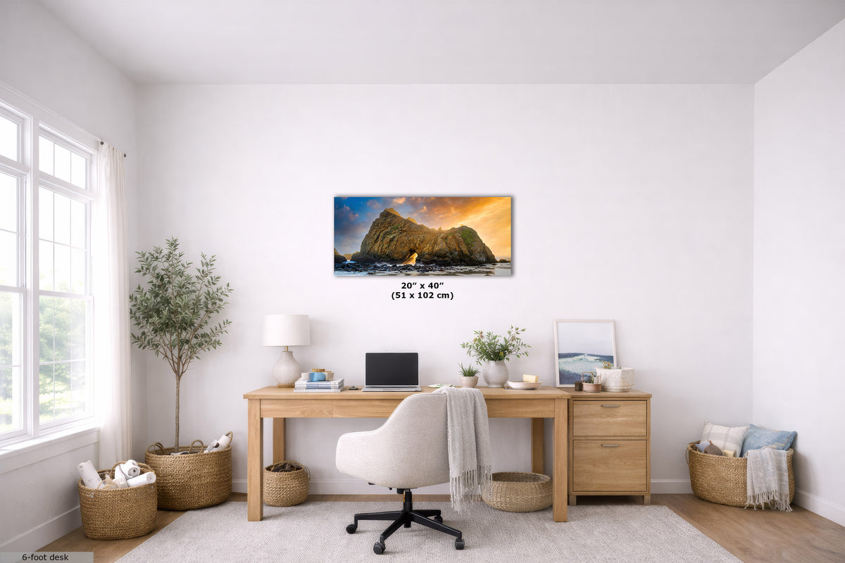 A framed wall art print depicting a rocky coastal landscape at sunset hangs above a wooden desk in a bright, modern home office. The print is shown with dimensions labeled in the center: 20 x 40 in (51 x 102 cm).