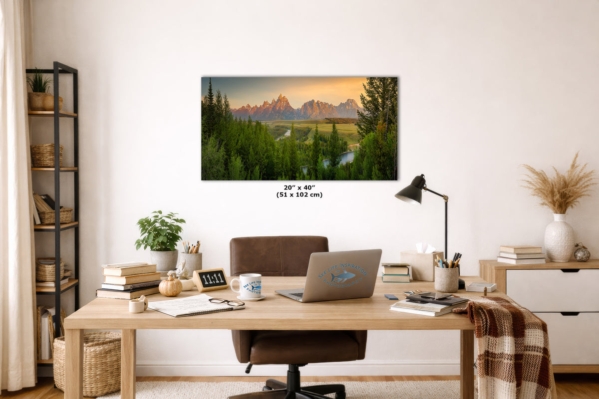 A framed wall art print showing a mountain landscape at sunset hangs above a wooden desk in a styled home office.