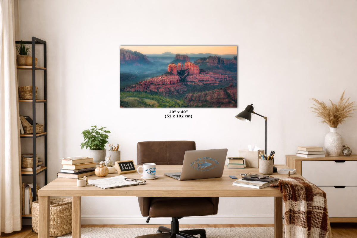 A wall art print showing a canyon landscape with red rock formations and blue sky, displayed above a wooden desk in a styled home office. The print includes size text reading 20 x 40 inches (51 x 102 cm).