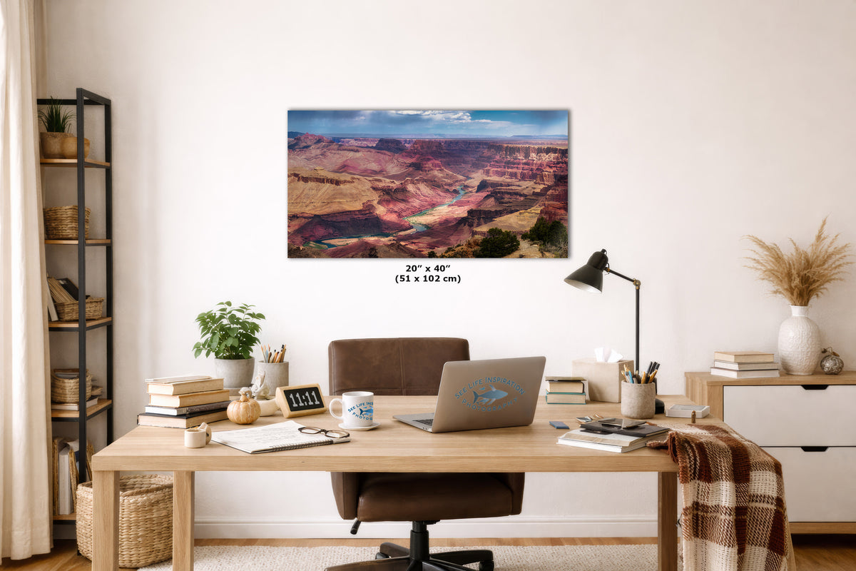 A rectangular wall art print showing a colorful canyon landscape hangs above a wooden desk in a styled home office. The print includes size text reading 20 x 40 inches (51 x 102 cm).