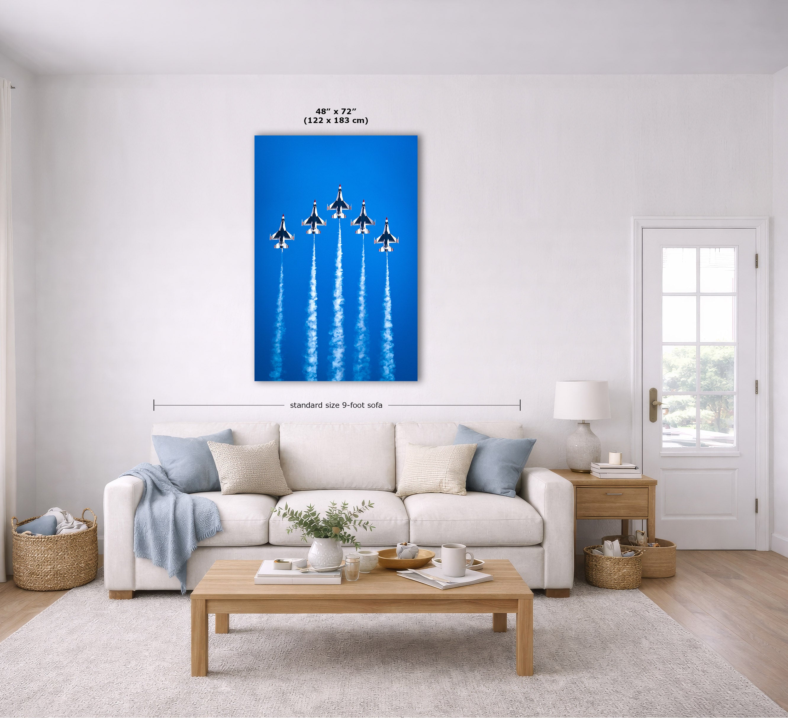 A vertical wall art print showing five fighter jets flying in a blue sky with white contrails, displayed above a white sofa in a bright, modern living room. The image includes dimension lines and text indicating the print is 48" x 72" (122 x 183 cm) and is mounted on a 9-foot wall.