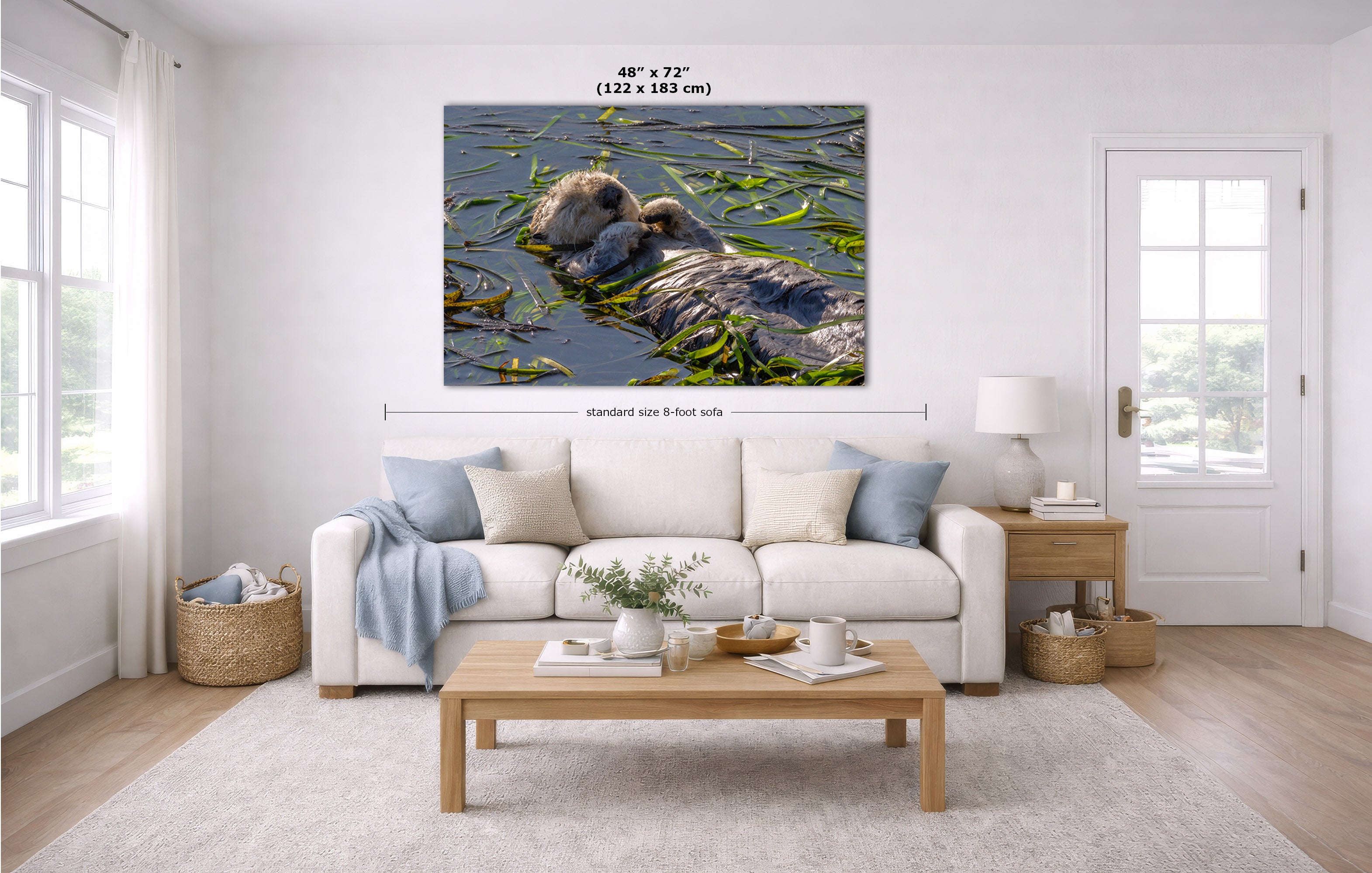 A large wall art print showing a mother sea otter in water with reeds, displayed in a bright modern living room above a white sofa. The image includes dimension lines and text indicating the print is 48 x 72 inches (122 x 183 m) and standard size is 8 feet tall.