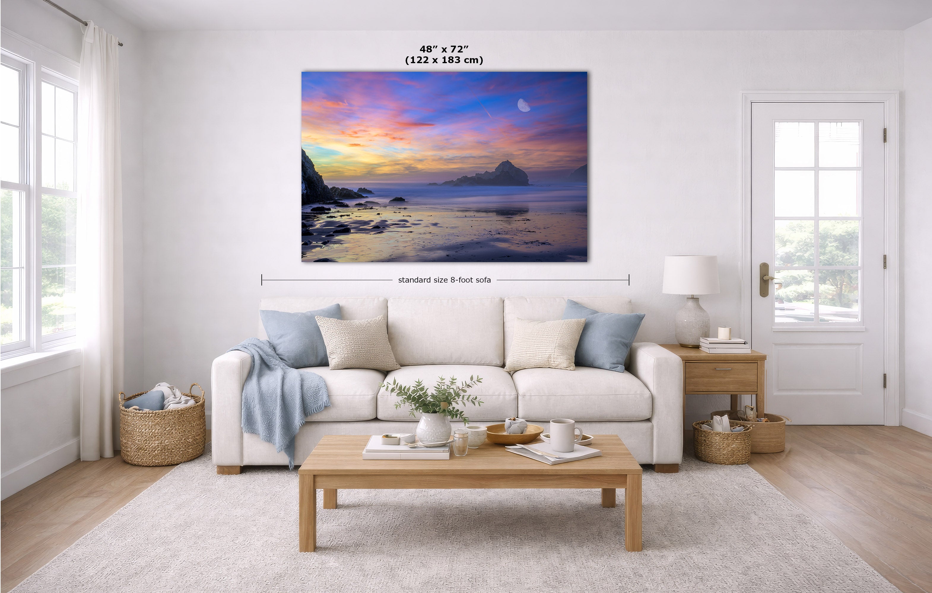 A large wall art print showing a colorful coastal sunset scene, displayed above a white sofa in a bright modern living room. Black measurement text at the top reads 48" x 72" (122 x 183 cm), and smaller text below indicates standard size 8 feet tall.