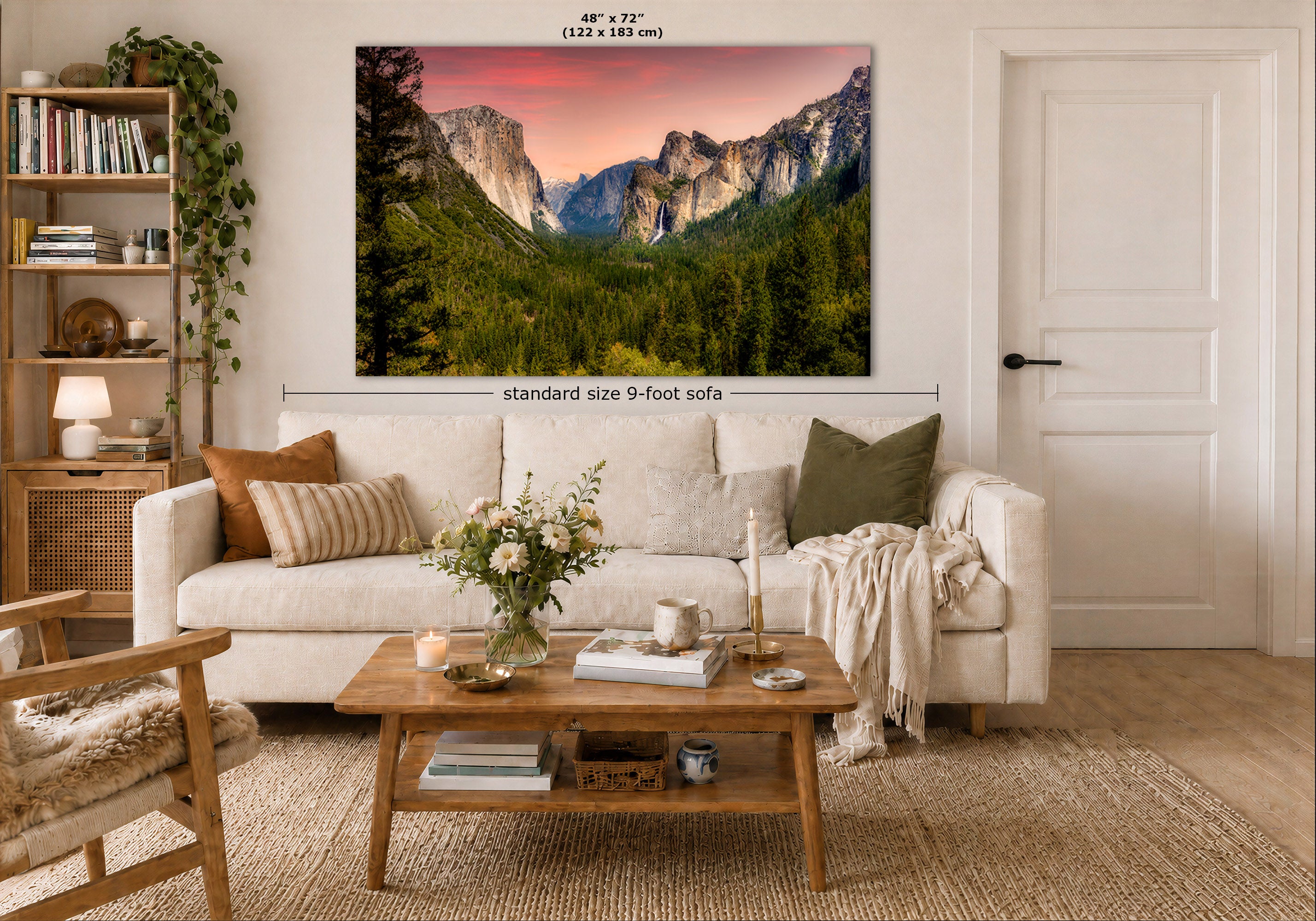 A wall art print showing a mountain valley landscape with a pink sunset sky, displayed above a white sofa in a styled living room. The image includes size labels indicating 48 x 72 inches and a note about standard size 9-foot sofa.