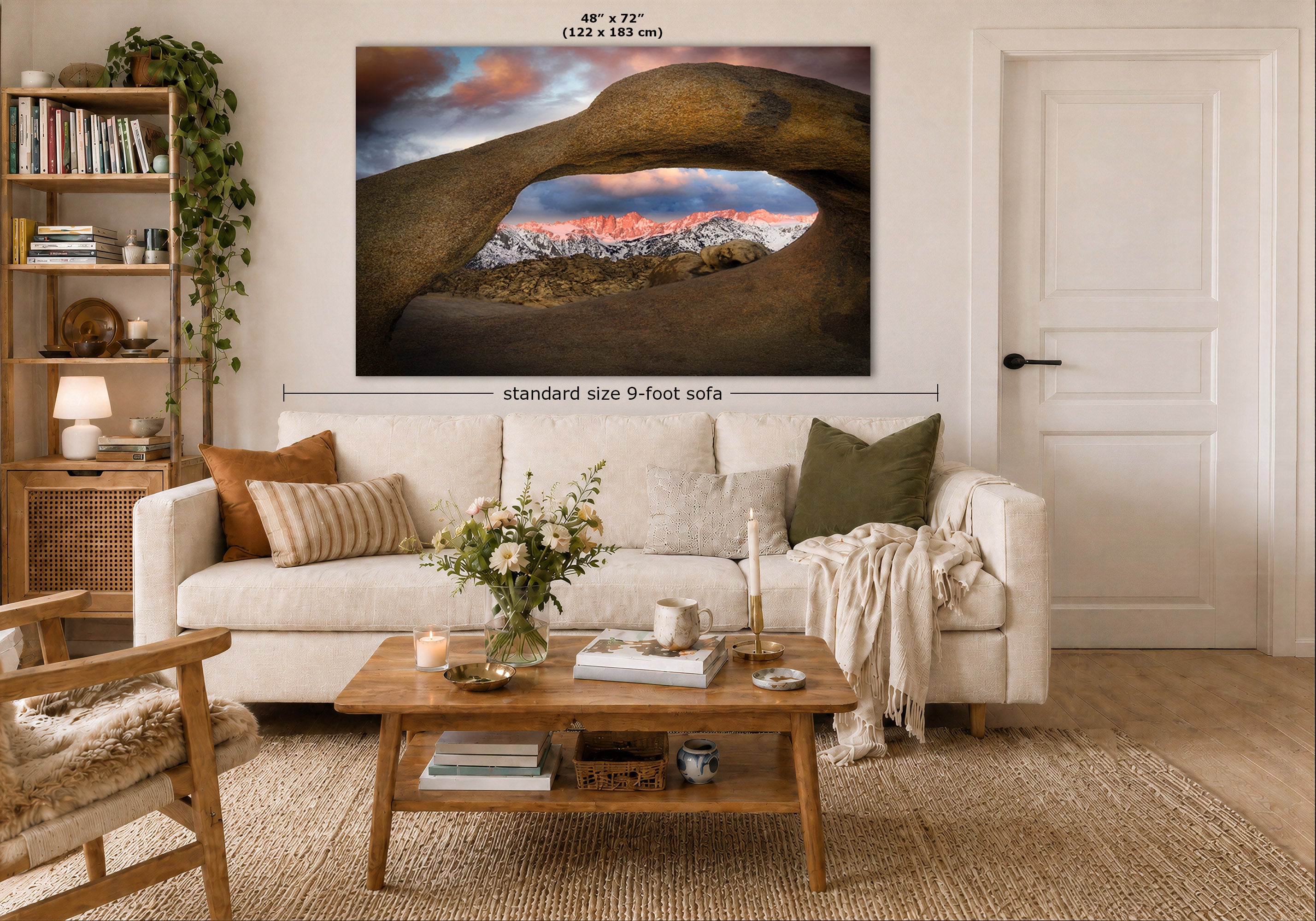 A large wall art print showing a natural stone arch over colorful mountains, displayed above a white sofa in a styled living room. Measurement text indicates the print is 48 x 72 inches, and a dimension label notes standard size 9-foot sofa placement.