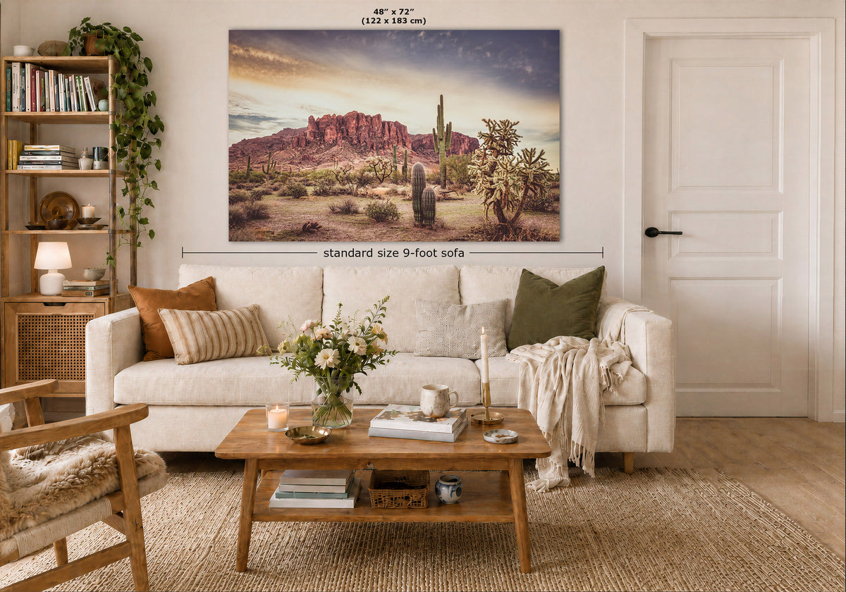 A large rectangular wall art print showing a desert canyon landscape with cacti and rock formations, displayed above a white sofa in a styled living room. The print includes size text reading 48" x 72" (122 x 183 cm) and a dimension line labeled standard size 9-foot sofa.