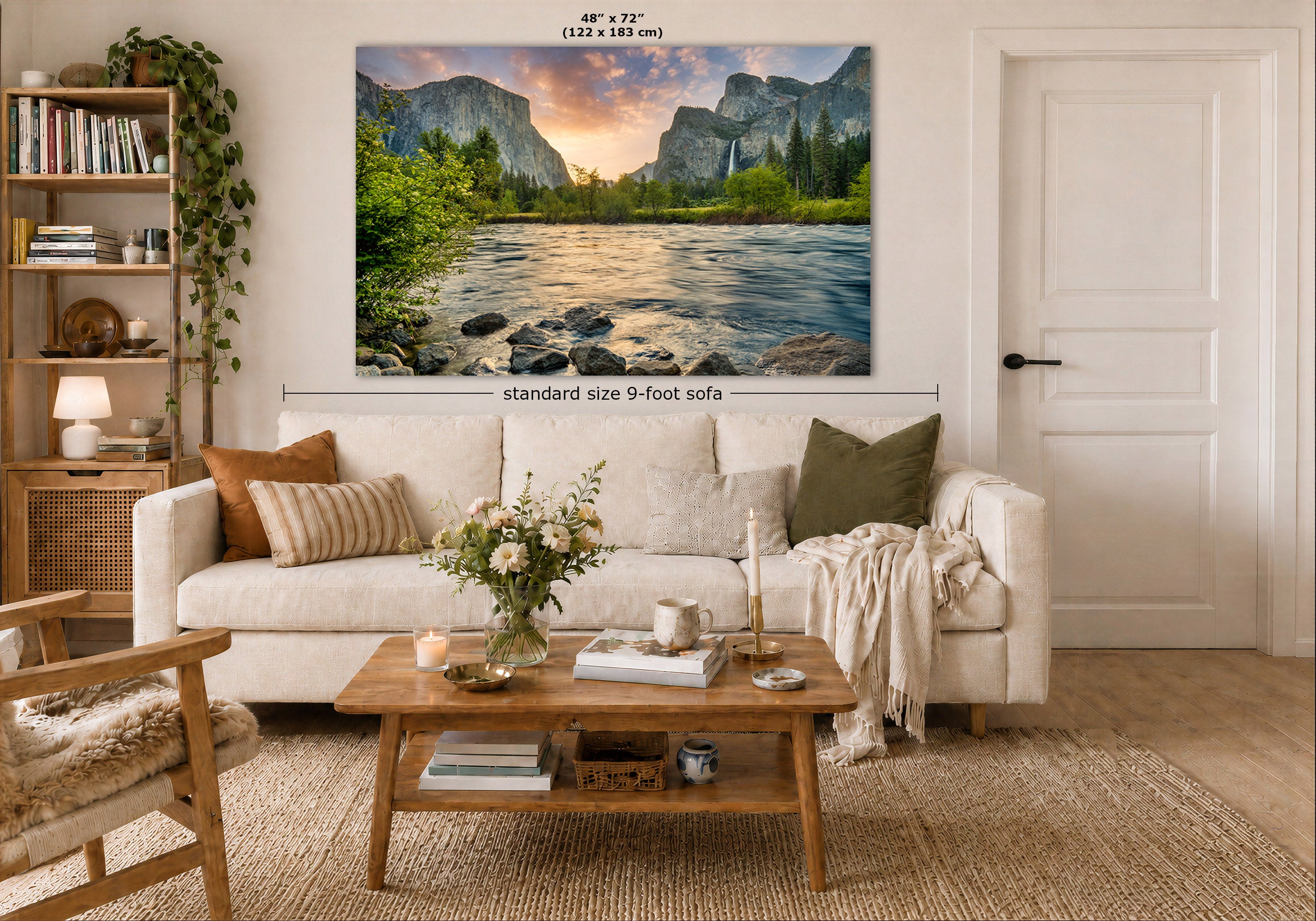 A large framed wall art print showing a mountain river landscape with a sunset is displayed above a white sofa in a styled living room. Measurement text and arrows indicate the print is 48 x 72 inches, and the image includes room context with a coffee table, sofa, shelving, and door.