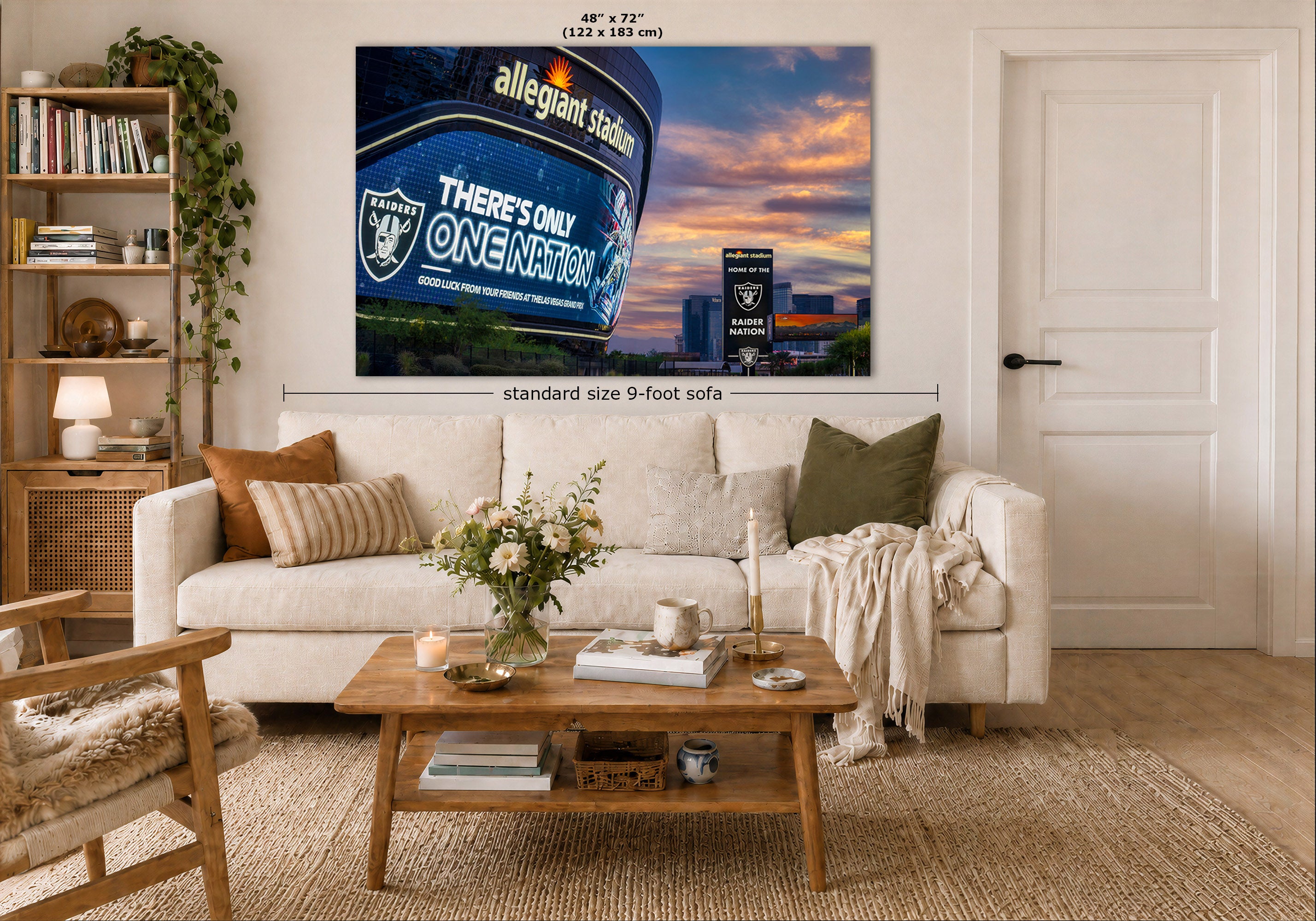 A large wall art print showing a stadium night scene with a blue sign and sunset sky, displayed above a white sofa in a styled living room. The print includes size text reading 48 x 72 inches and a dimension marker for a standard 9-foot sofa.