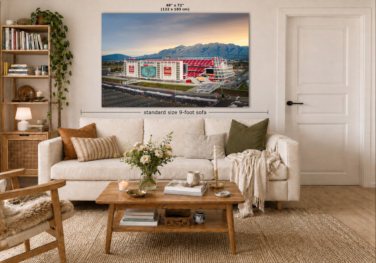A large Levi's Stadium sunrise wall art print showing a stadium scene with mountains and a sunset sky, displayed above a white sofa in a styled living room. Measurement text indicates the print is 48 x 72 inches, and a dimension callout notes a 9-foot sofa below.