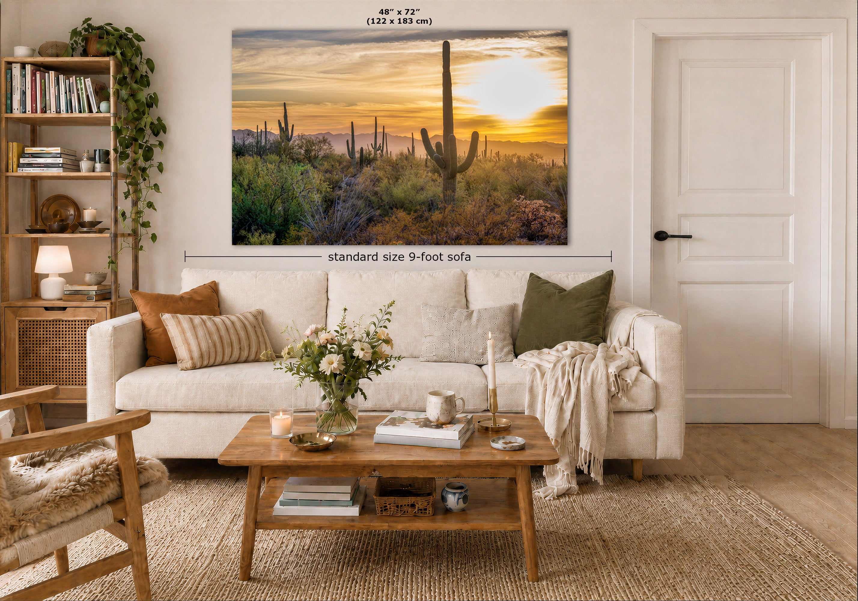 A large rectangular wall art print showing a desert sunset with saguaro cacti, displayed above a white sofa in a styled living room. Measurement text at the top reads 48 x 72 inches, and a dimension line indicates standard size 9-foot sofa placement.