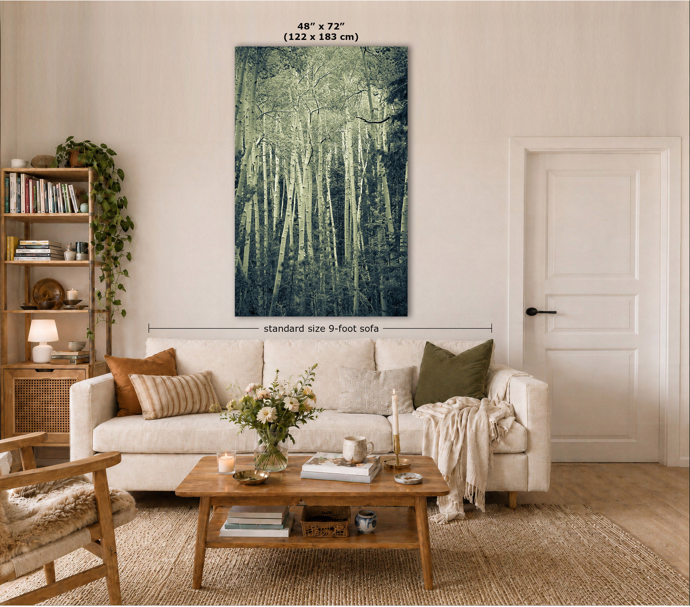 A vertical forest canvas print in muted blue-green tones hangs on a beige wall above a white sofa in a styled living room. The image includes size annotations: '48" x 72" (122 x 183 cm)' at the top and 'standard size 9-foot sofa' with a dimension line across the sofa below the artwork.