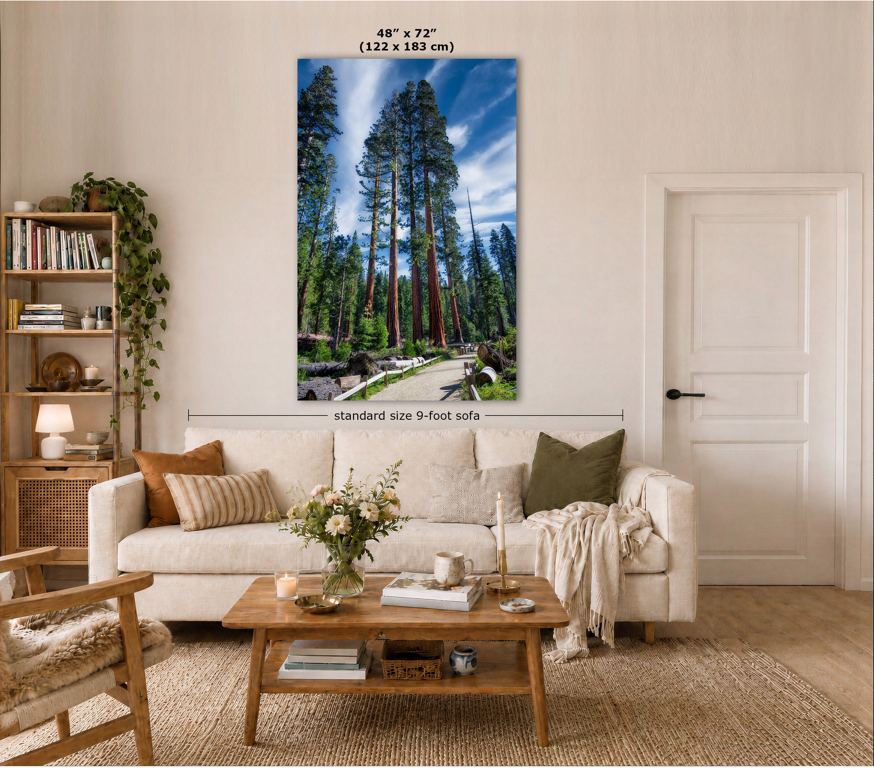A vertical canvas tall sequoia tree wall art print depicting a forest scene and a winding path, displayed above a cream sofa in a styled living room. The image includes size dimension text indicating 48" x 72" (122 x 183 cm) and a label reading standard size 9-foot sofa.