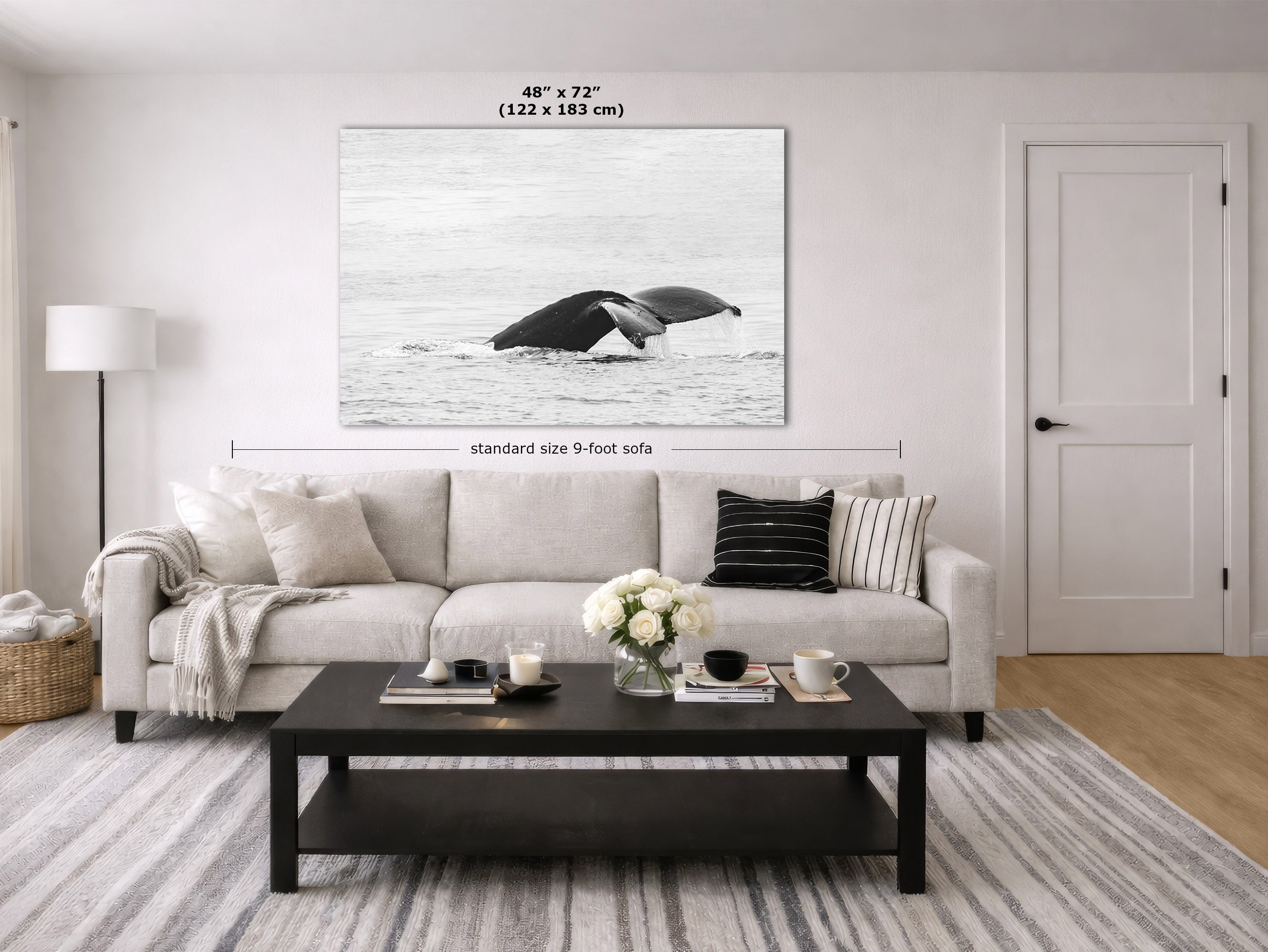 A large black and white whale print displayed on a wall in a modern living room setting above a light beige sofa. The image includes dimension lines and text indicating the print is 48" x 72" (122 x 183 cm) and the sofa is standard size 9-foot.