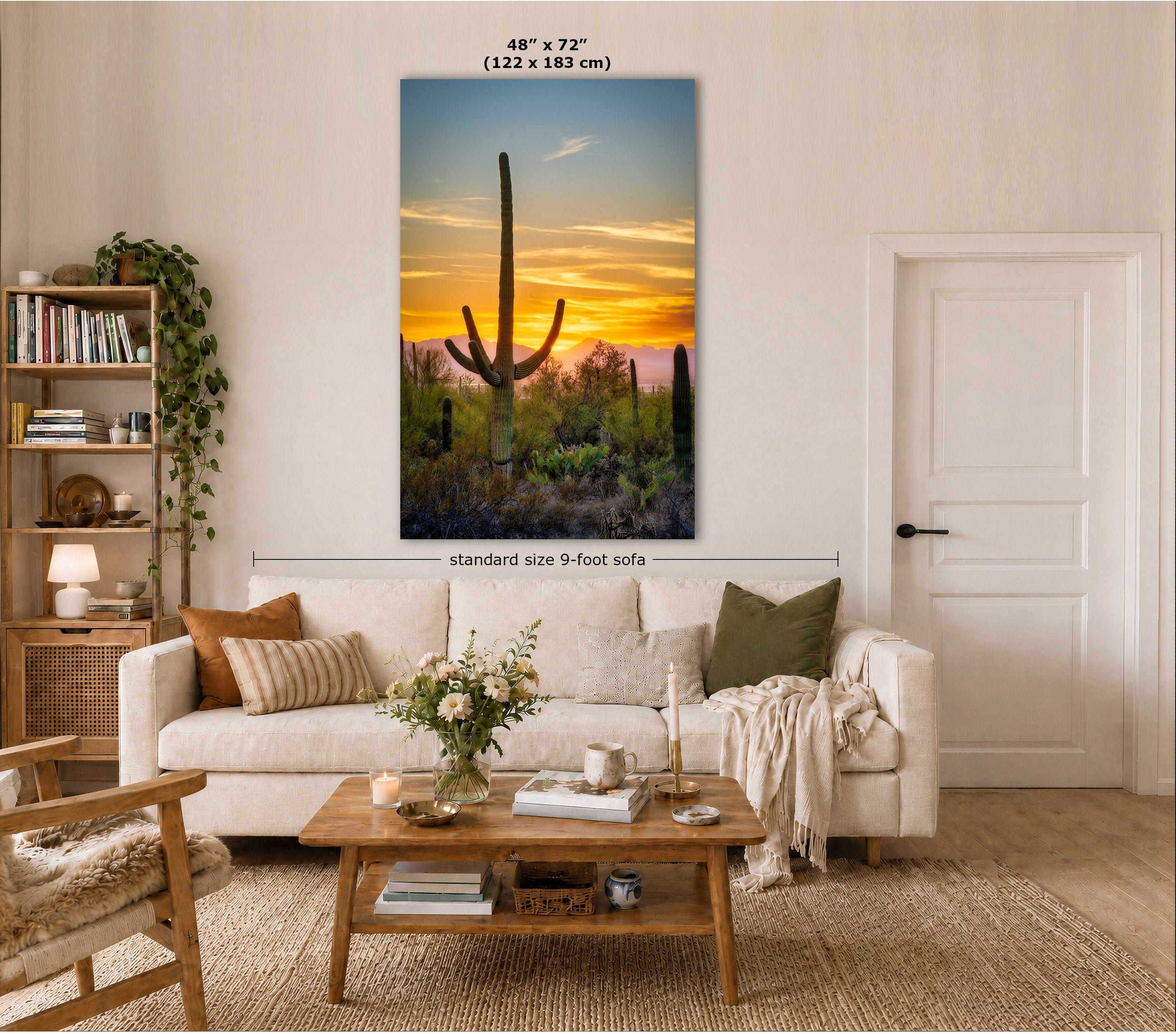 A large vertical canvas wall art print showing a desert cactus silhouette at sunset, displayed above a white sofa in a styled living room. The image includes size text indicating 48" x 72" (122 x 183 cm) and a dimension line labeled standard size 9-foot sofa.