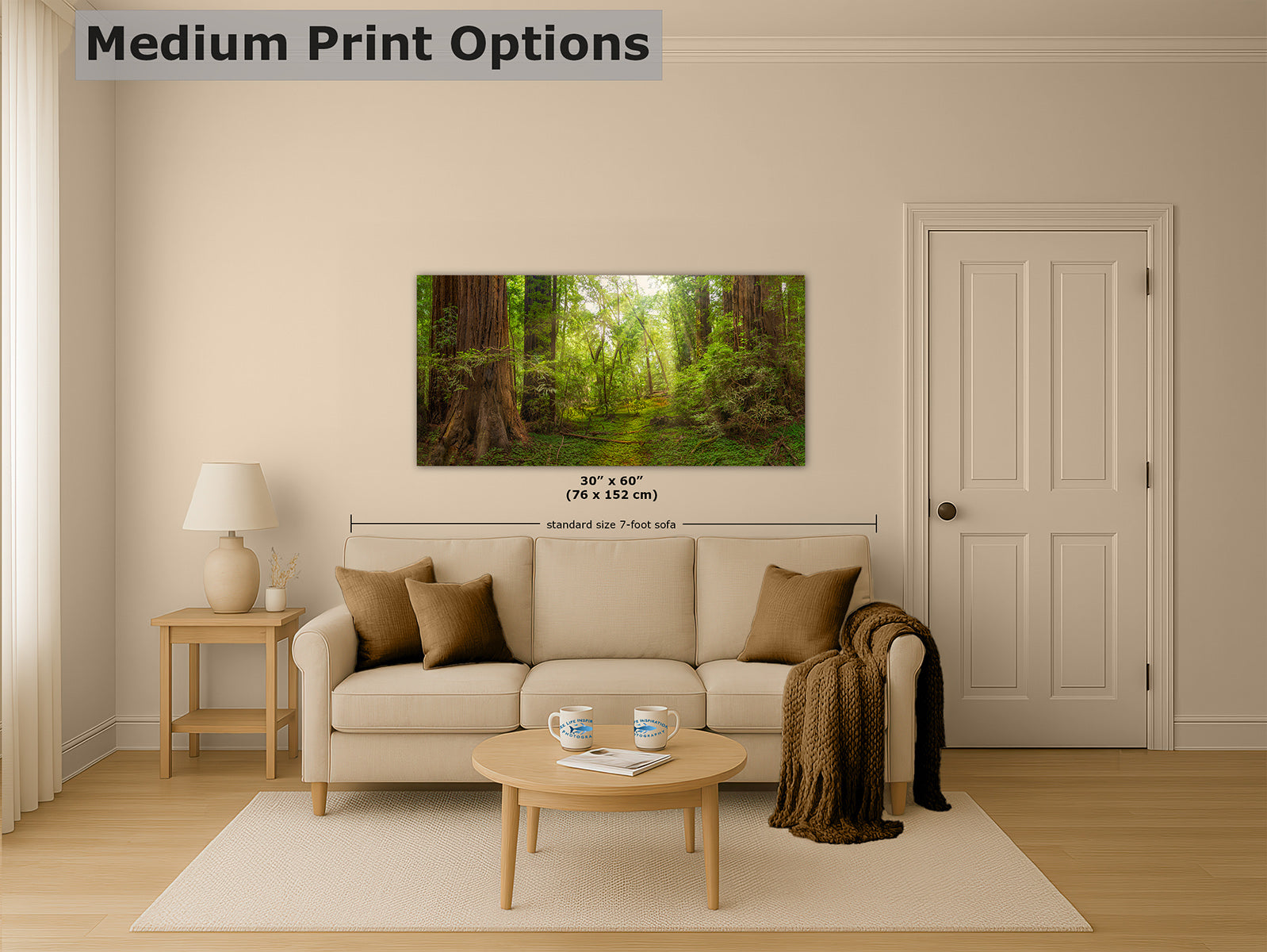 A Redwood forest wall art print is displayed above a beige sofa in a styled living room. The print shows a lush green woodland scene with trees and sunlight.