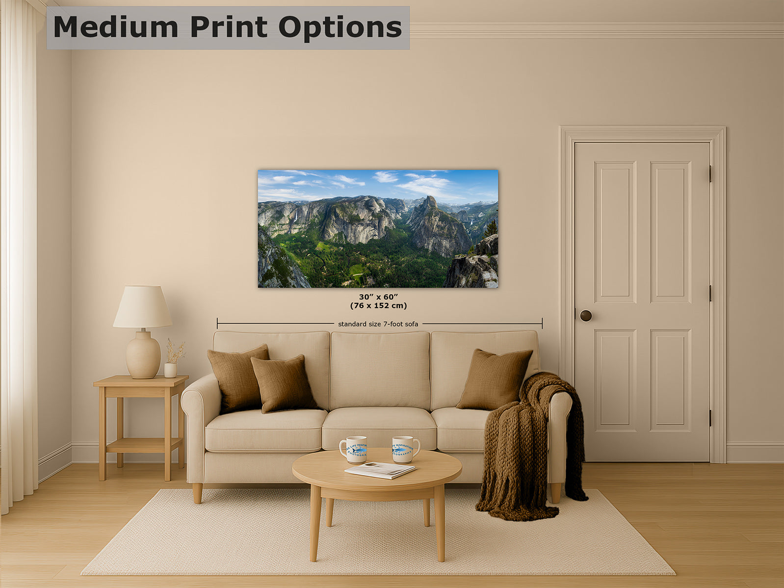 A living room mockup showing a landscape wall art print of Yosemite Valley from Glacier Point, shown above a beige sofa. The print depicts a mountain valley scene with green hills, rocky cliffs, and blue sky.