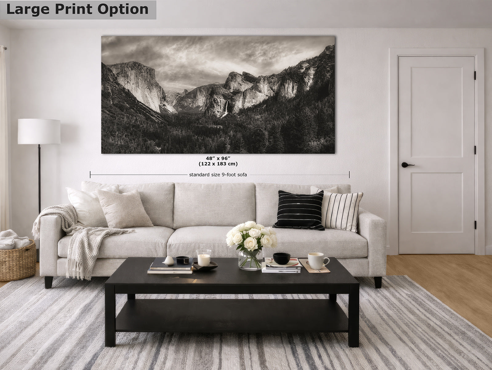 A large black-and-white landscape fine art print of Yosemite Valley, displayed on a white wall above a light beige sofa in a modern living room setting. The image includes a 'Large Print Option' label in the top left corner and dimension markings below the canvas.