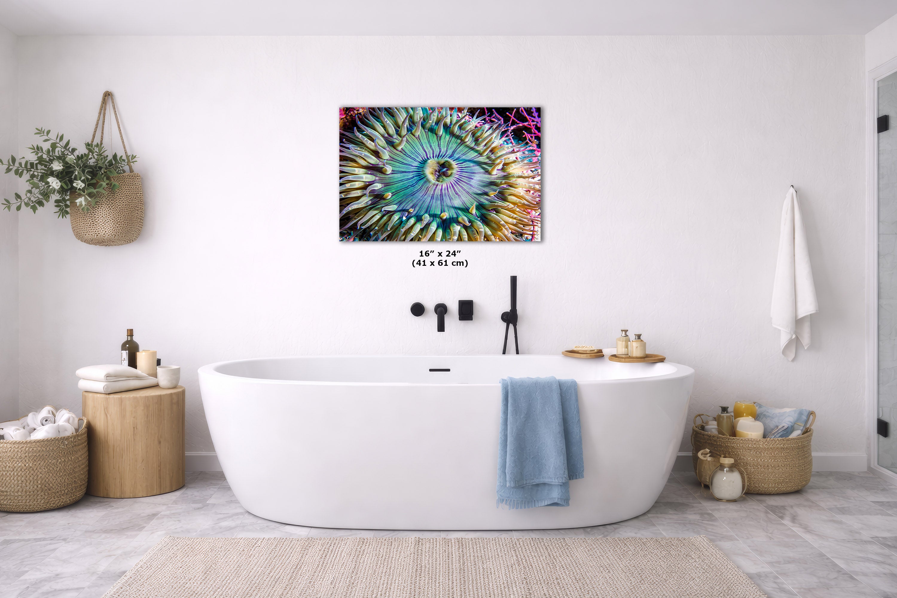 A colorful abstract spiral wall art print hangs above a white freestanding bathtub in a bright, modern bathroom with neutral decor and a blue towel draped over the tub.