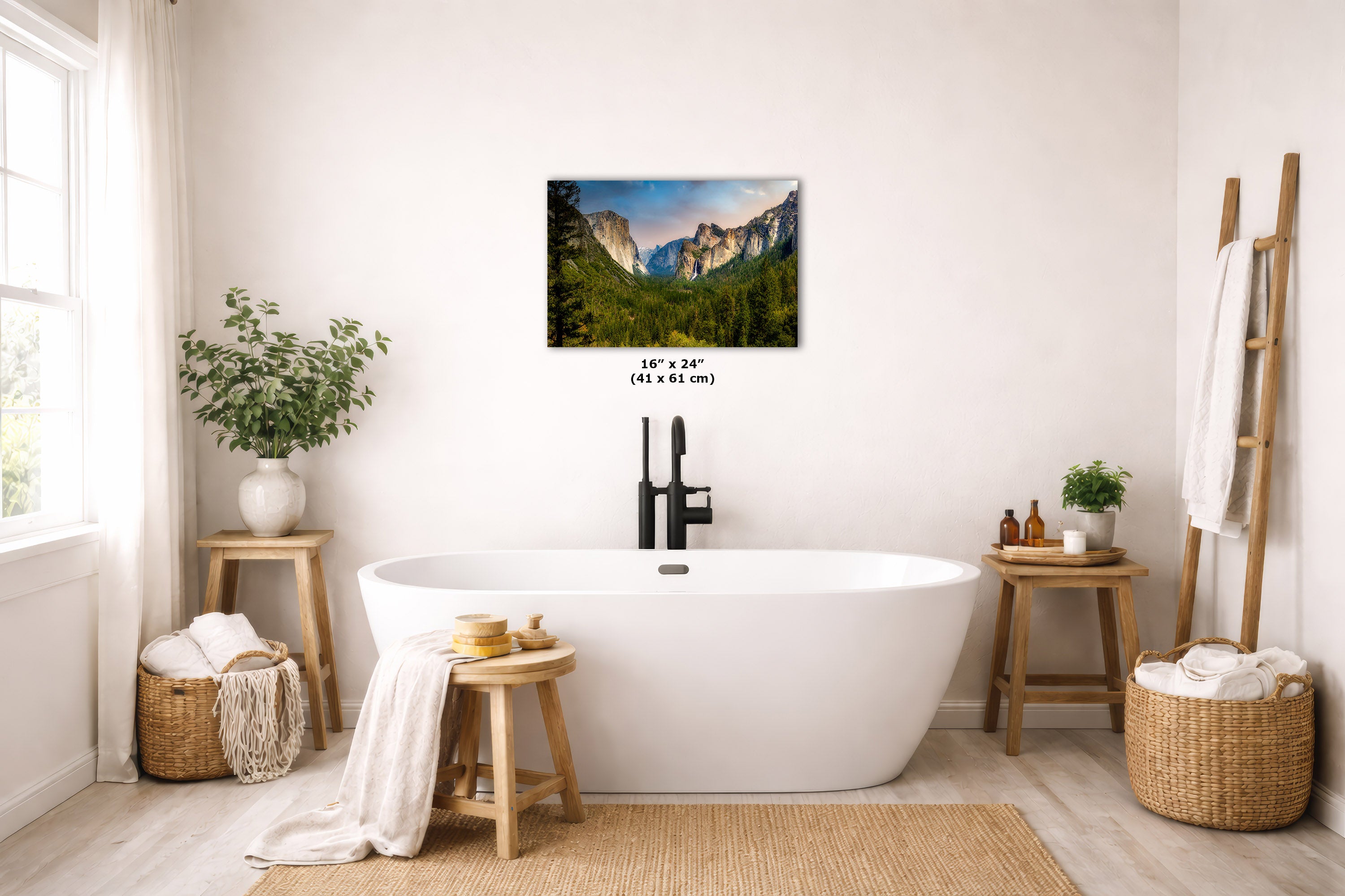 A wall art print depicting a waterfall in a rocky mountain landscape, displayed above a white freestanding bathtub in a bright, modern bathroom with wooden stools, plants, and woven baskets.