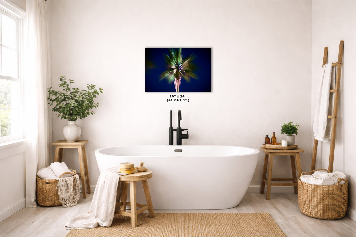 A wall art print showing an abstract palm tree, displayed above a white freestanding bathtub in a bright, modern bathroom with wooden stools, plants, and woven baskets.