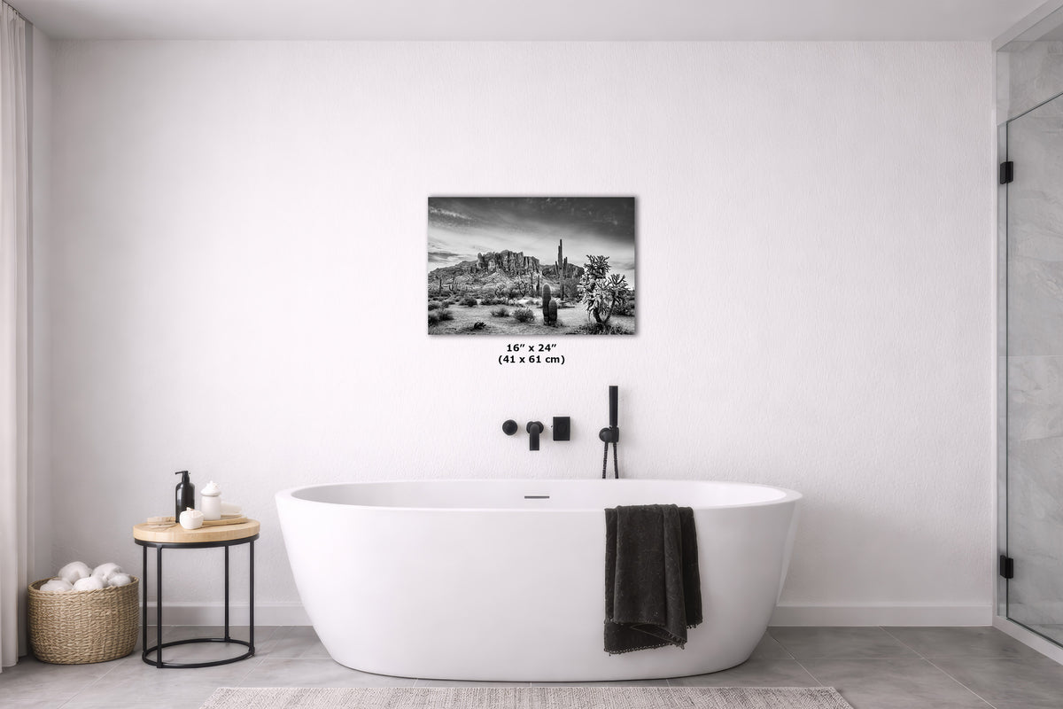 A black and white landscape art print displayed on a white wall above a modern freestanding bathtub in a minimalist bathroom setting.
