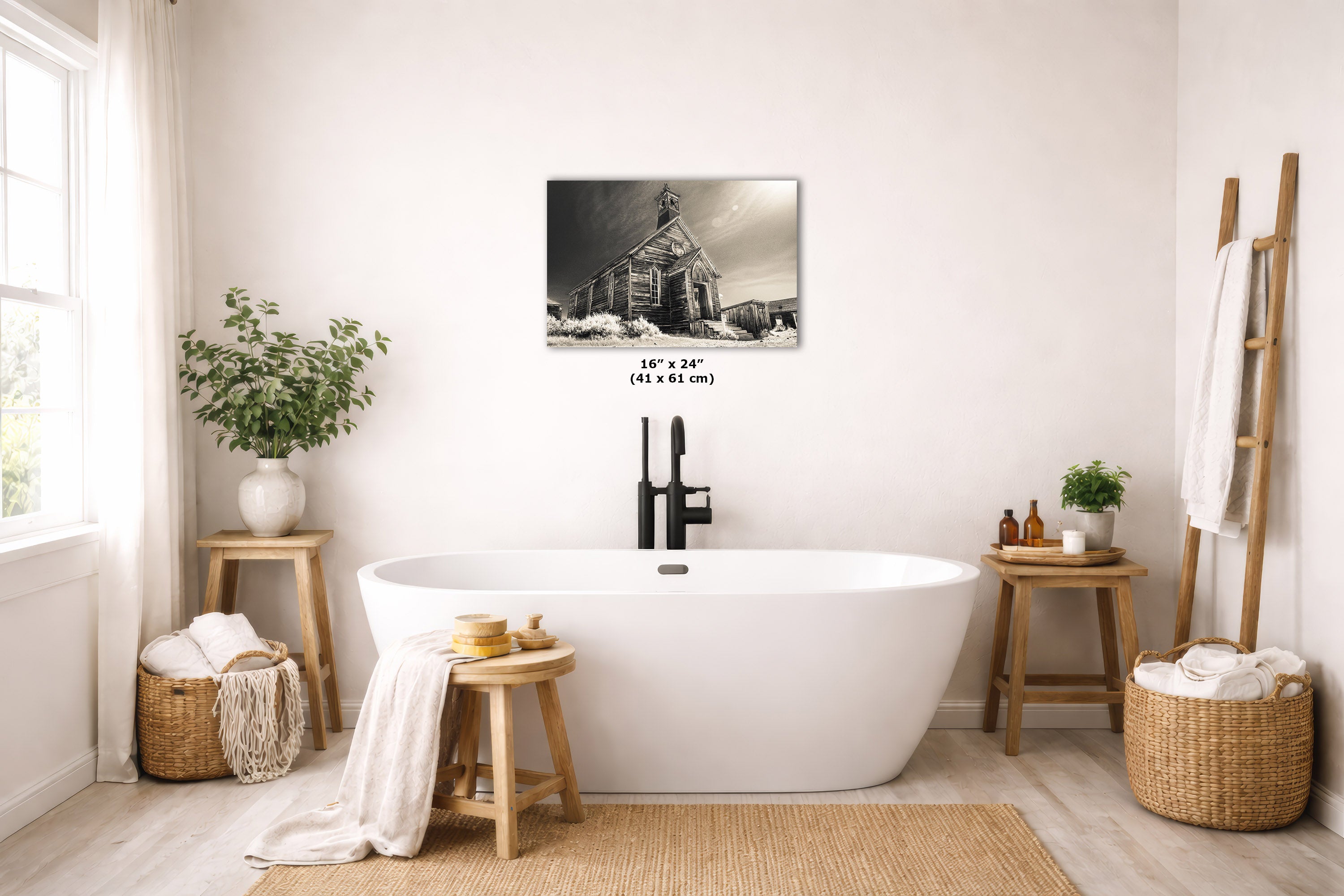 A nostalgic art print depicting a rustic cabin in a snowy landscape, displayed on a wall above a white freestanding bathtub in a bright, modern bathroom setting.