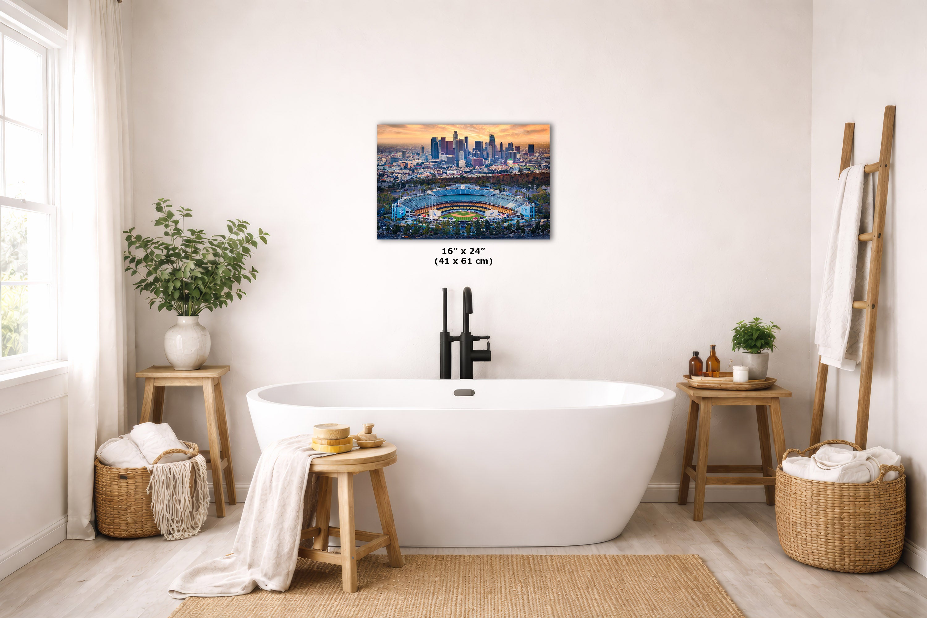 A freestanding bathtub in a bright, modern bathroom with a wall-mounted city skyline art print above it. The room includes wooden stools, woven baskets, plants, and a ladder shelf with towels.