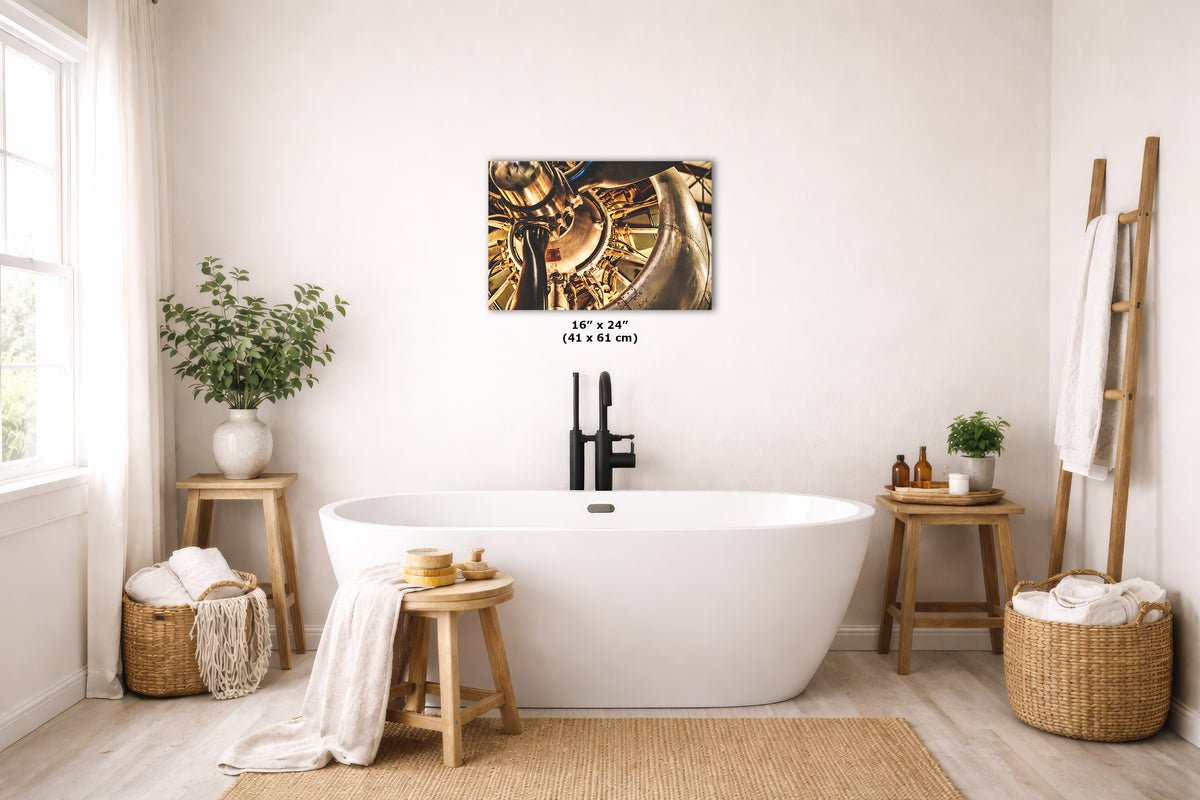 A wall art print of a Studebaker vintage airplane engine, displayed on a bathroom wall above a white freestanding bathtub. The print includes size text reading 16 x 24 (41 x 61 cm).