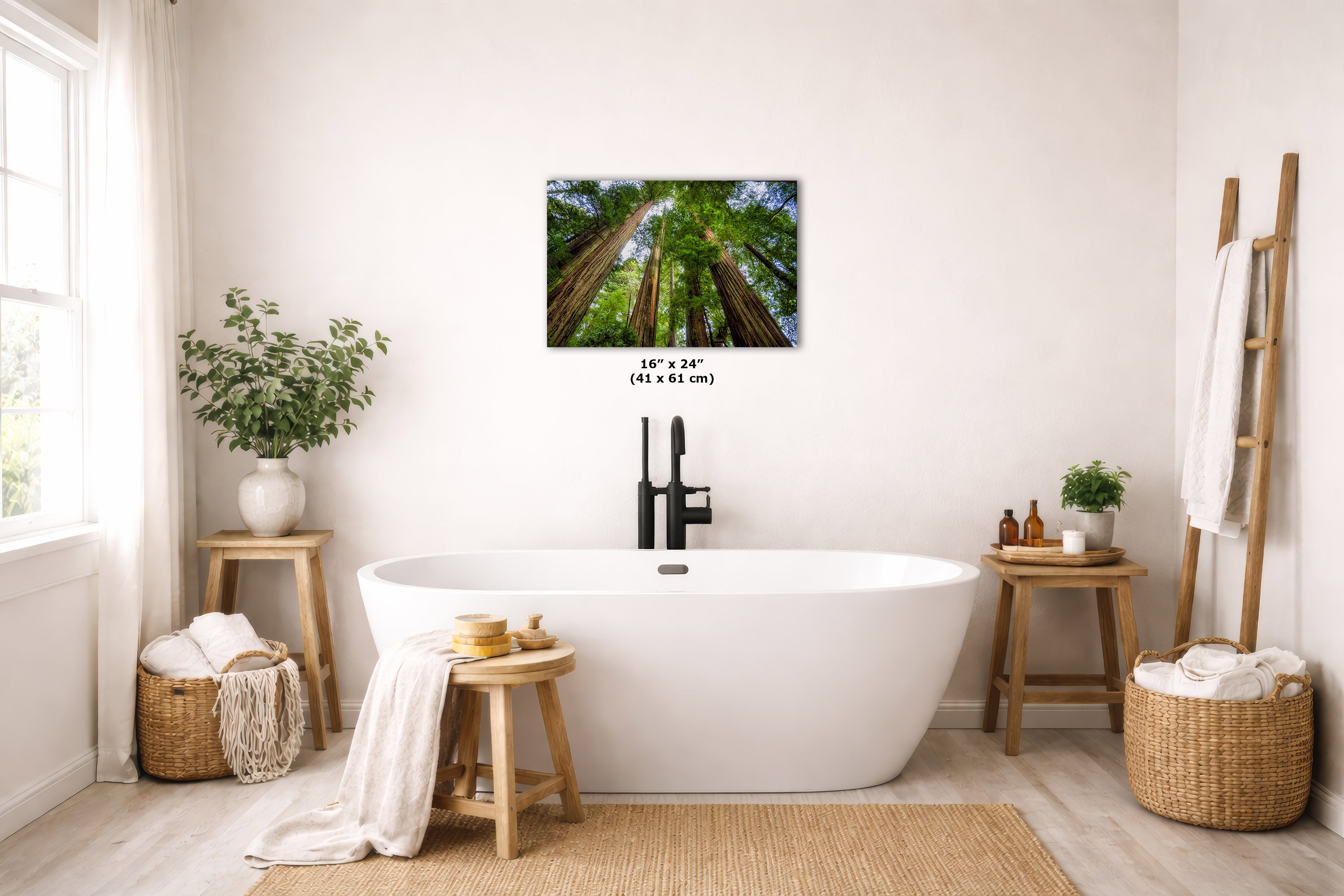 A freestanding white bathtub in a bright, neutral-toned bathroom with a redwood canopy tree art print above it. The scene includes wooden stools, woven baskets, plants, and a ladder-style towel rack.