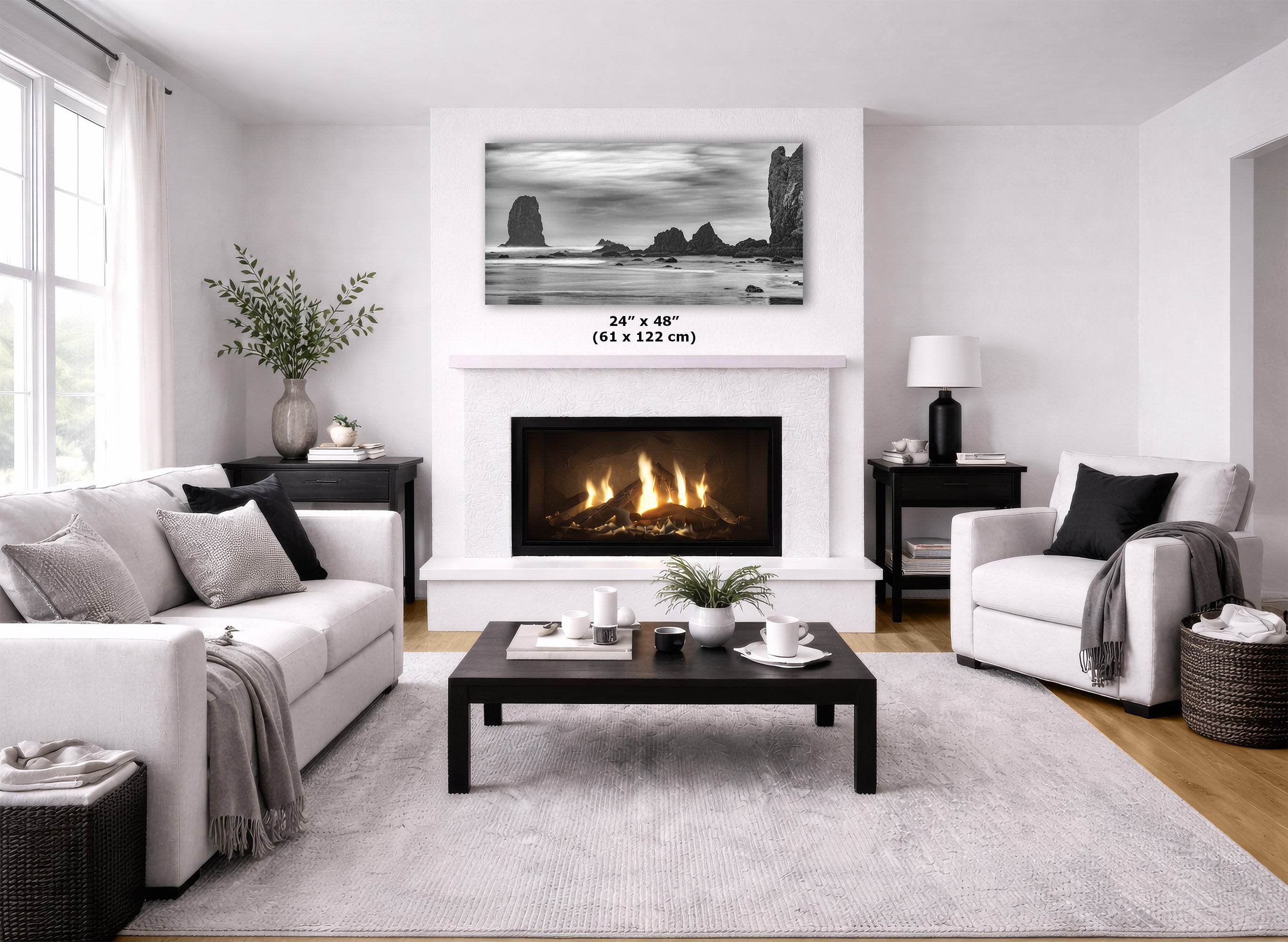 A framed black and white coastal landscape print displayed above a fireplace in a bright, modern living room. The print is labeled with dimensions '24" x 48" (61 x 122 cm)'.