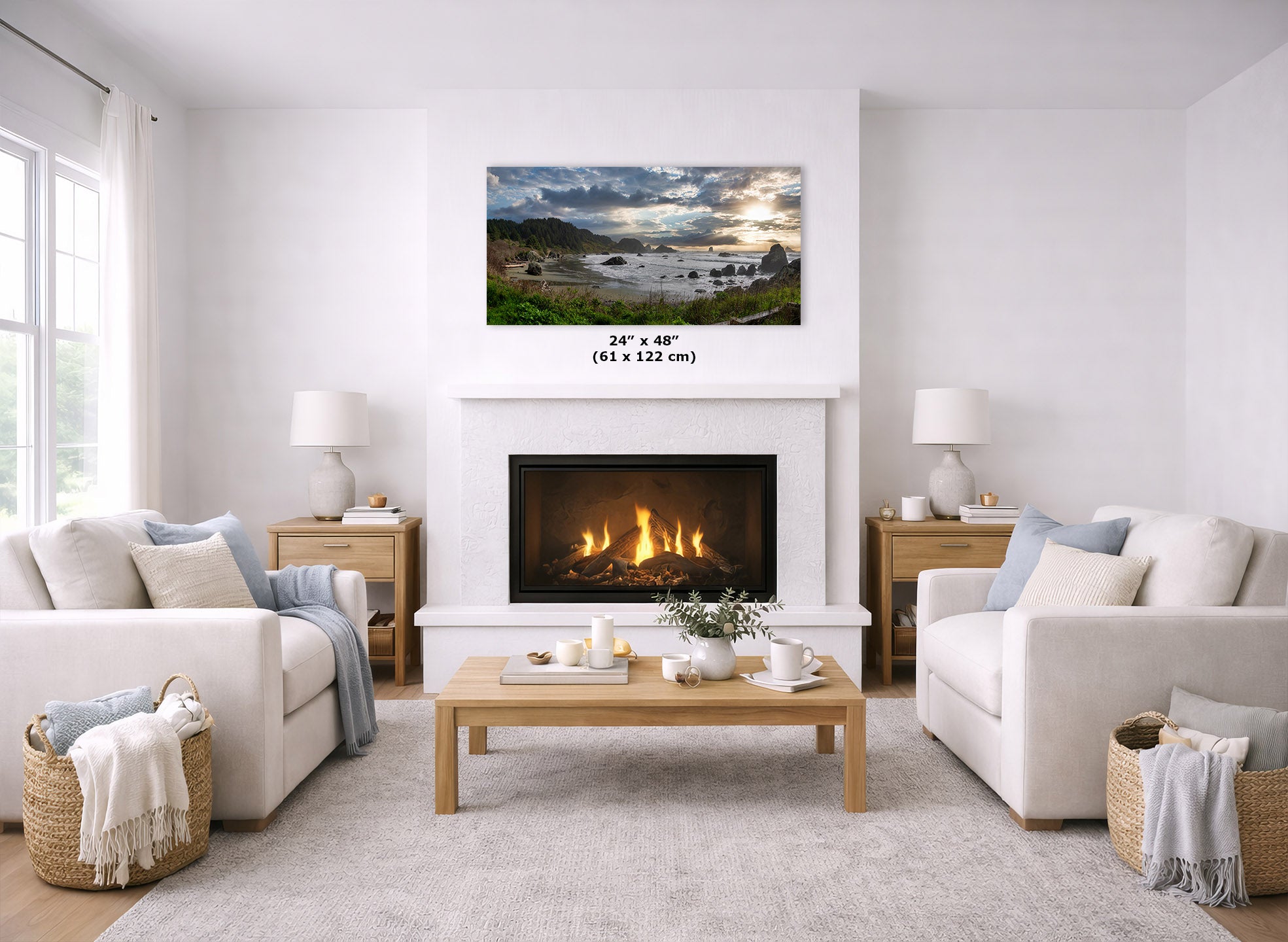 A framed landscape wall art print hangs above a fireplace in a bright, modern living room. The print depicts a dramatic lake or river scene with mountains, water, and a glowing sunset.